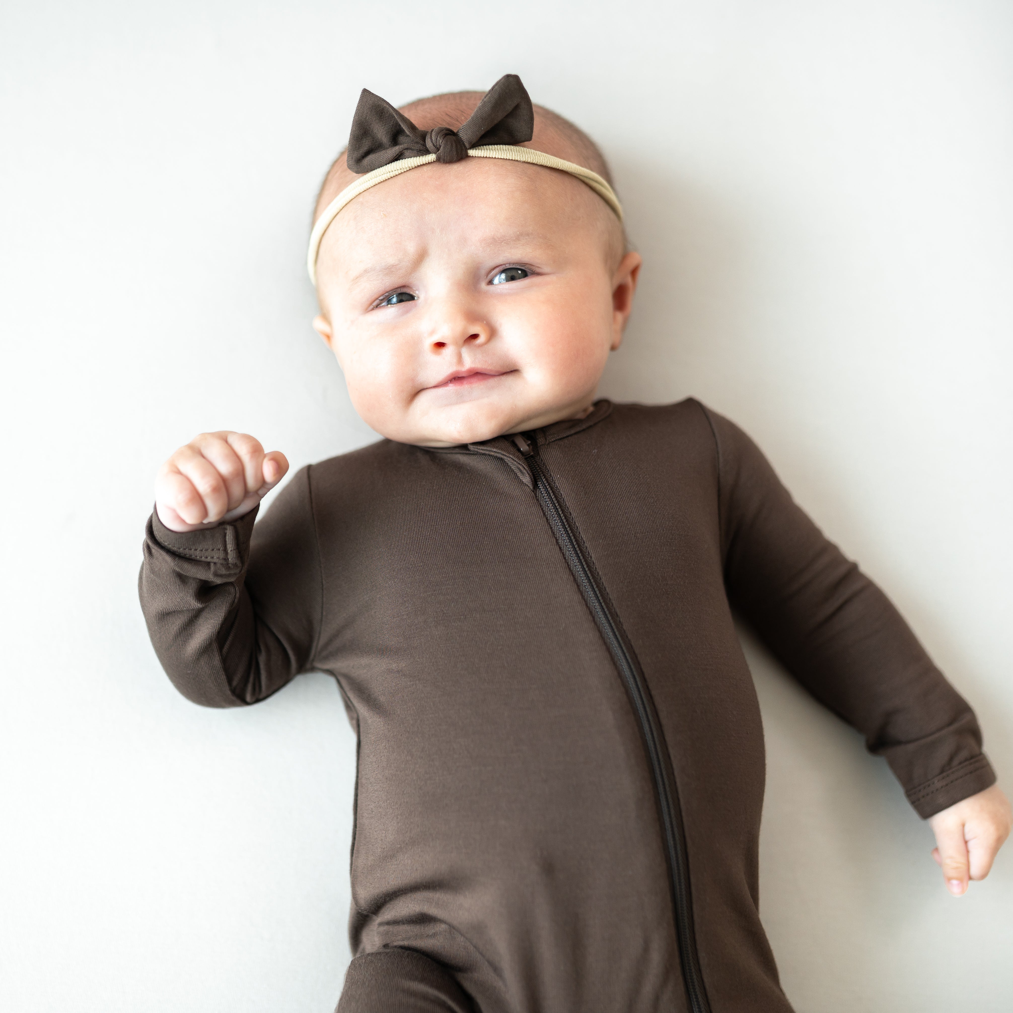 Infant wearing the Tiny Nylon Bow in Espresso paired with matching zippered romper