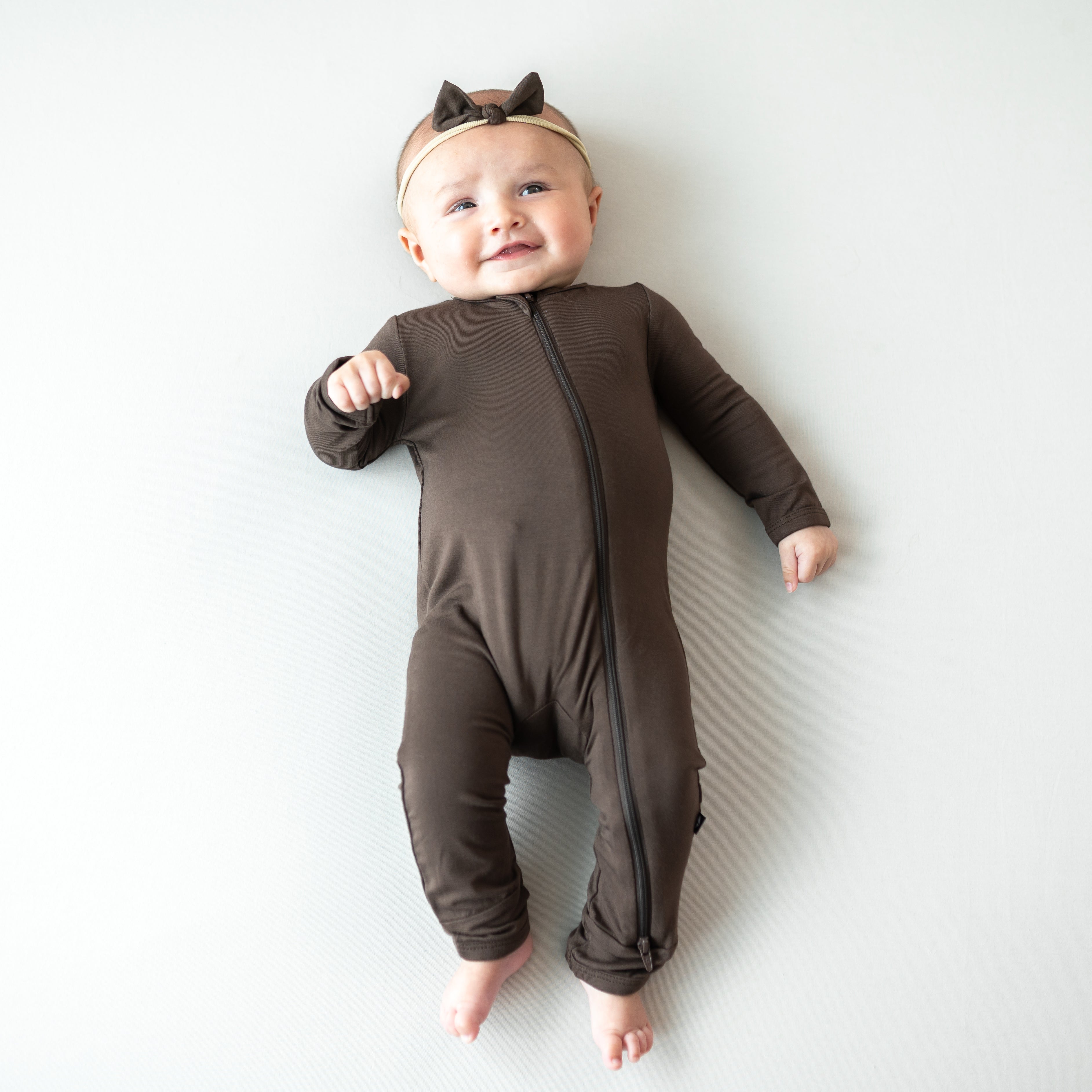 Infant wearing the Tiny Nylon Bow in Espresso paired with the matching zippered romper