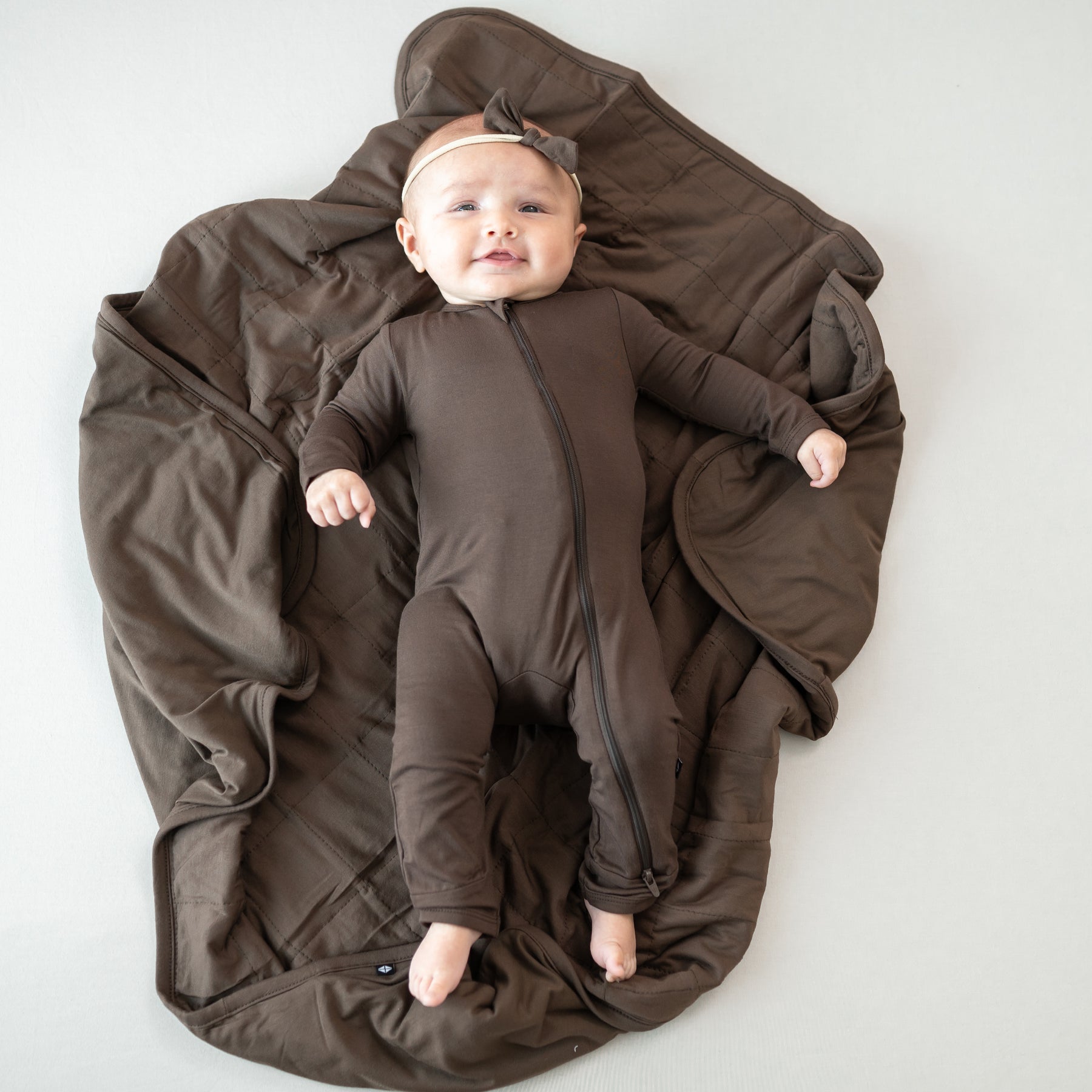 Infant laying on a Baby Blanket in Espresso 1.0 wearing a matching zippered romper
