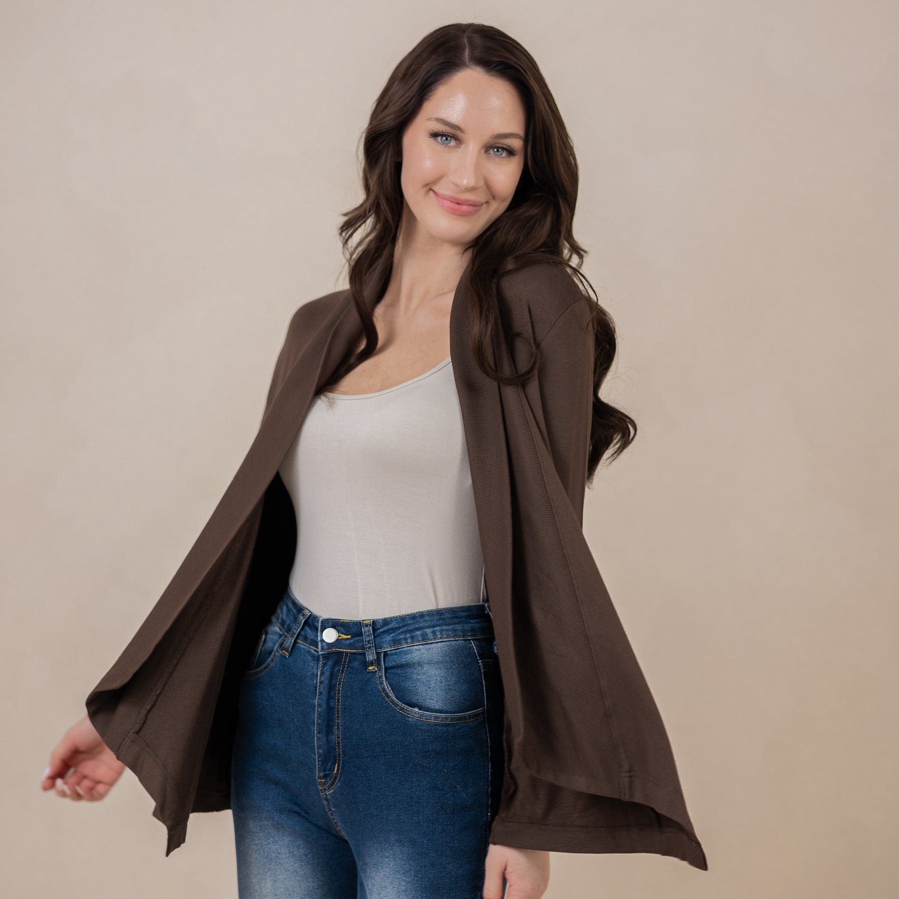Smiling female wearing the Women's French Terry Wrap Top in Espresso with a tan shirt and medium wash jeans