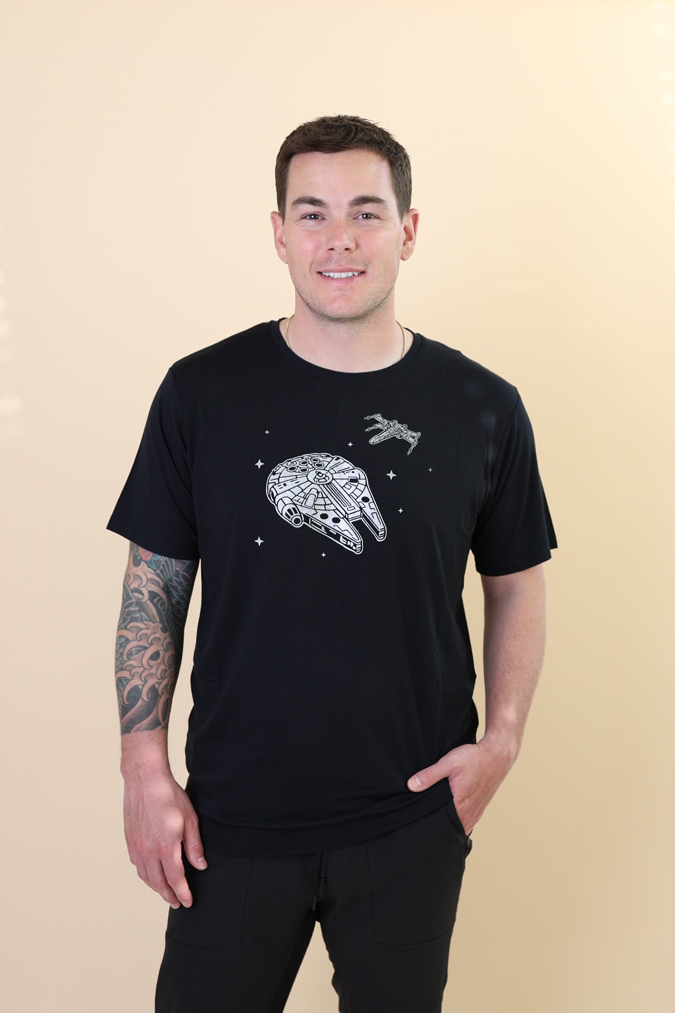 Male modeling the Men's Crew Neck Tee in Millennium Falcon™ with one hand in his jean pocket