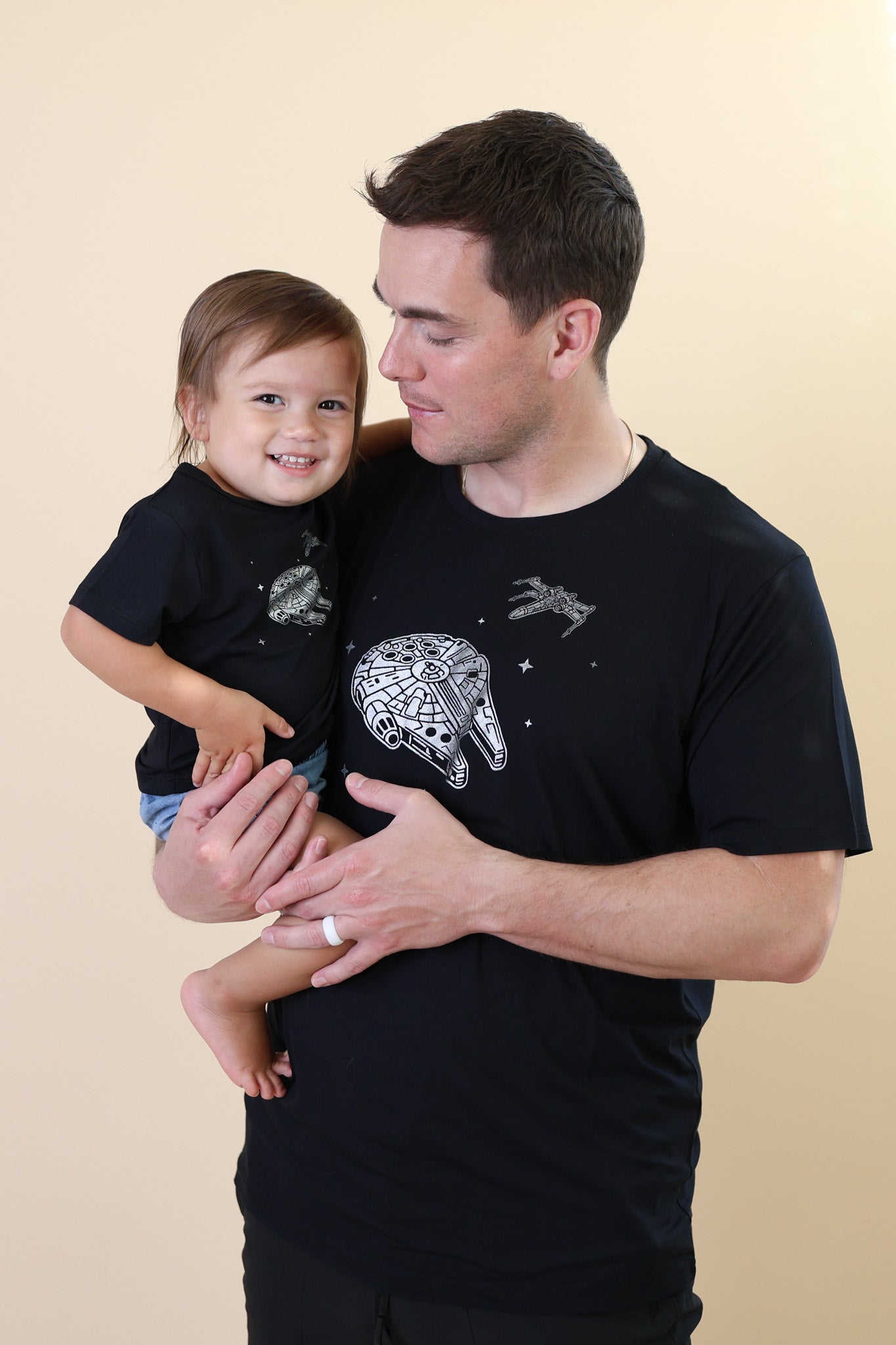 Father holding his son both matching in Crew Neck Tee in Millennium Falcon™