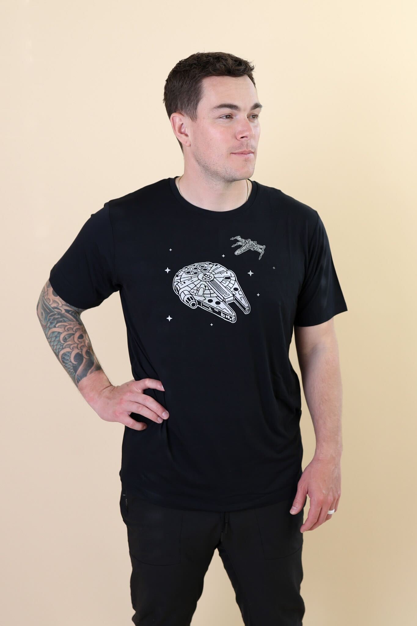 Male standing with one hand on his hip wearing the Men's Crew Neck Tee in Millennium Falcon™