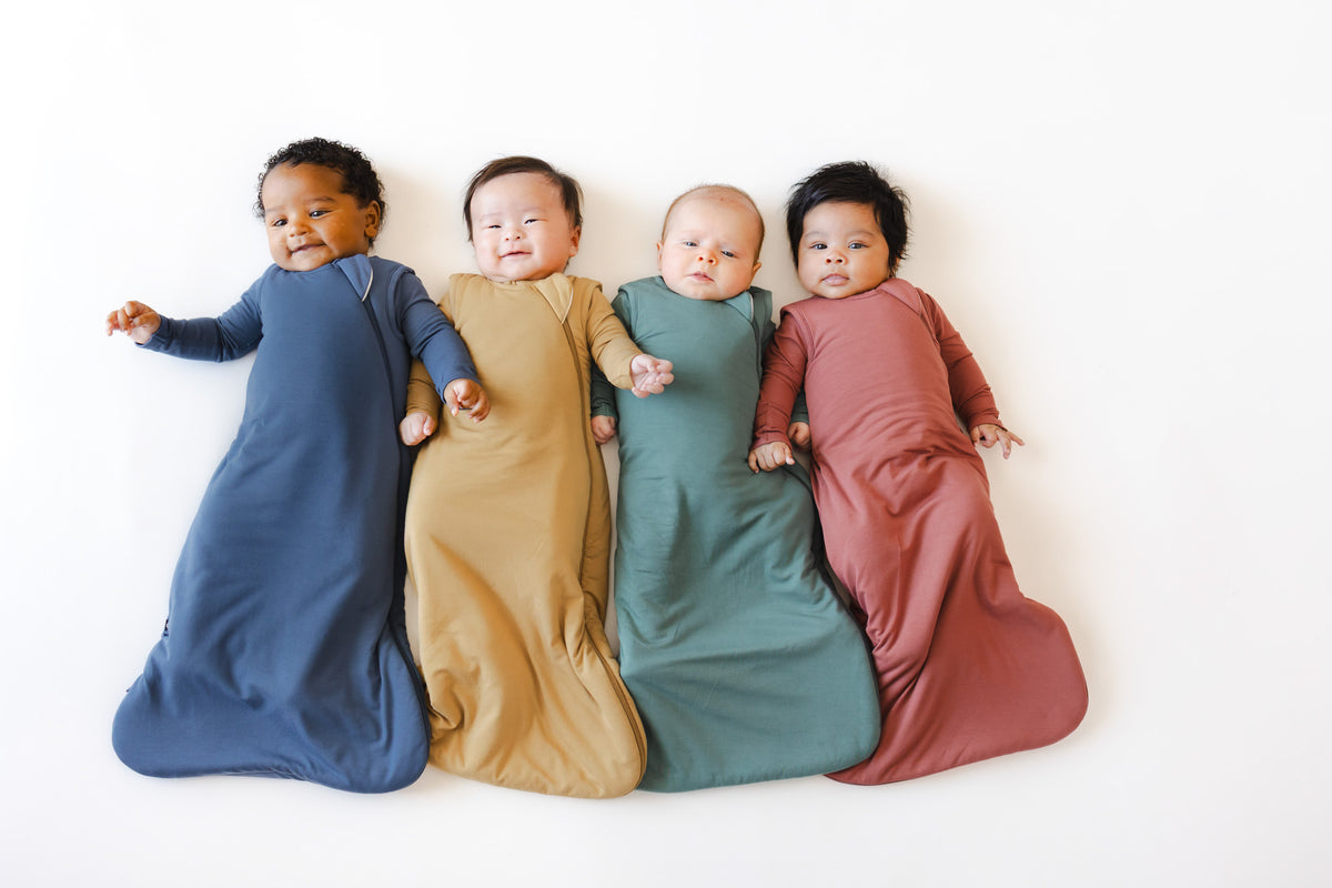 4 babies laying down in sleep bags.