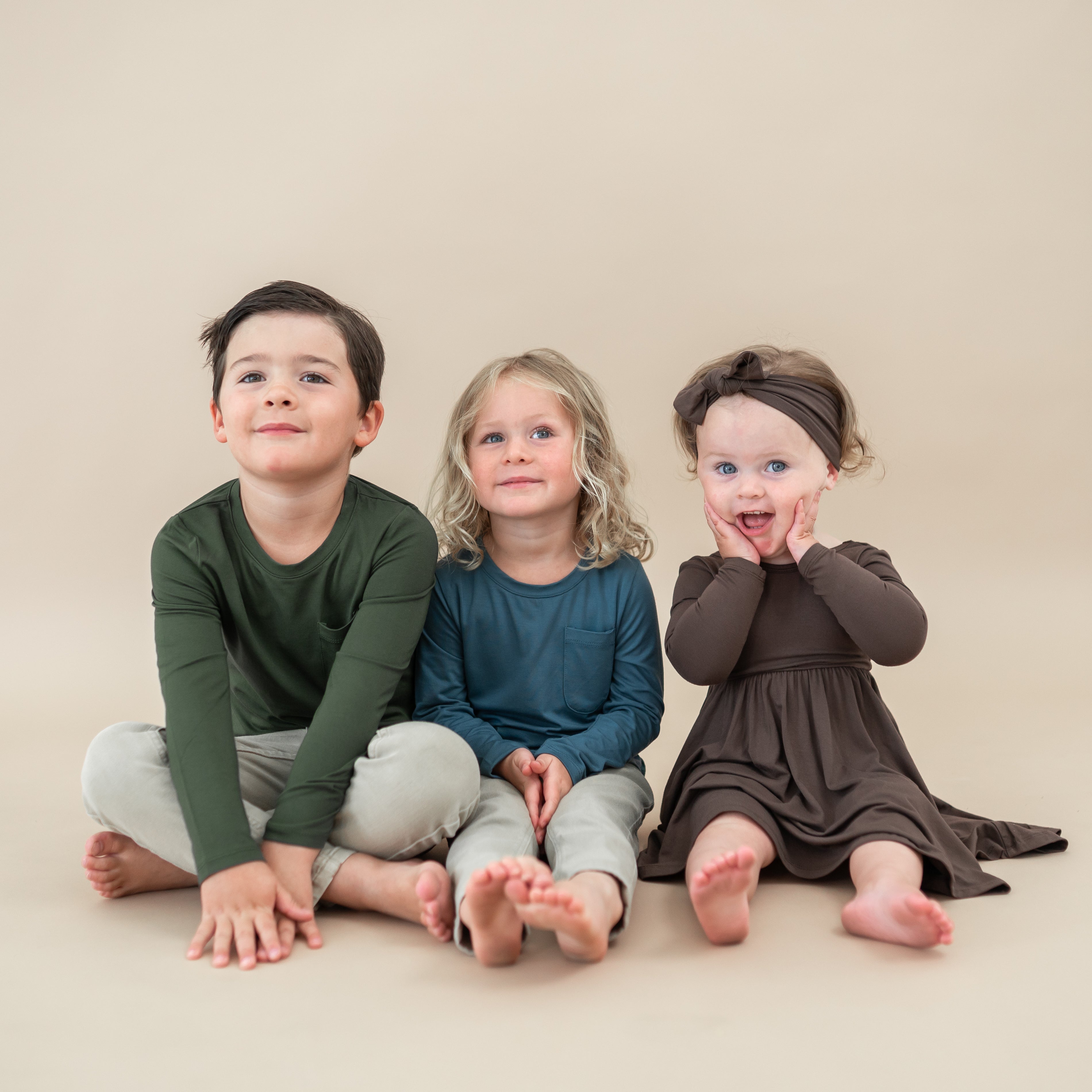 Child group photo of fall colors. Pictured is the Long Sleeve Twirl Dress in Espresso, Atlantic long sleeve crew neck and Fir long sleeve crew neck