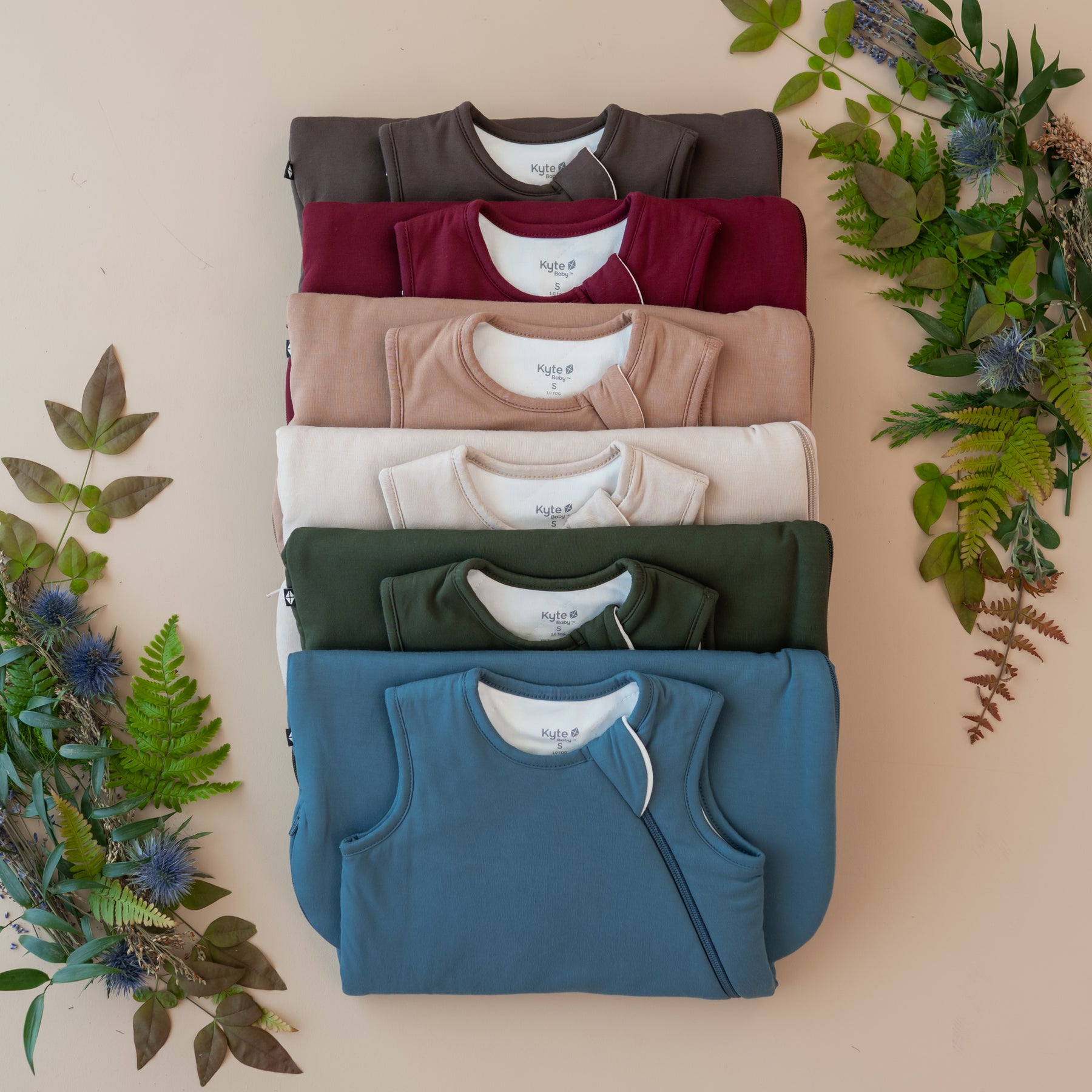 Stack of kyte baby folded sleep bags with a natural leafy background