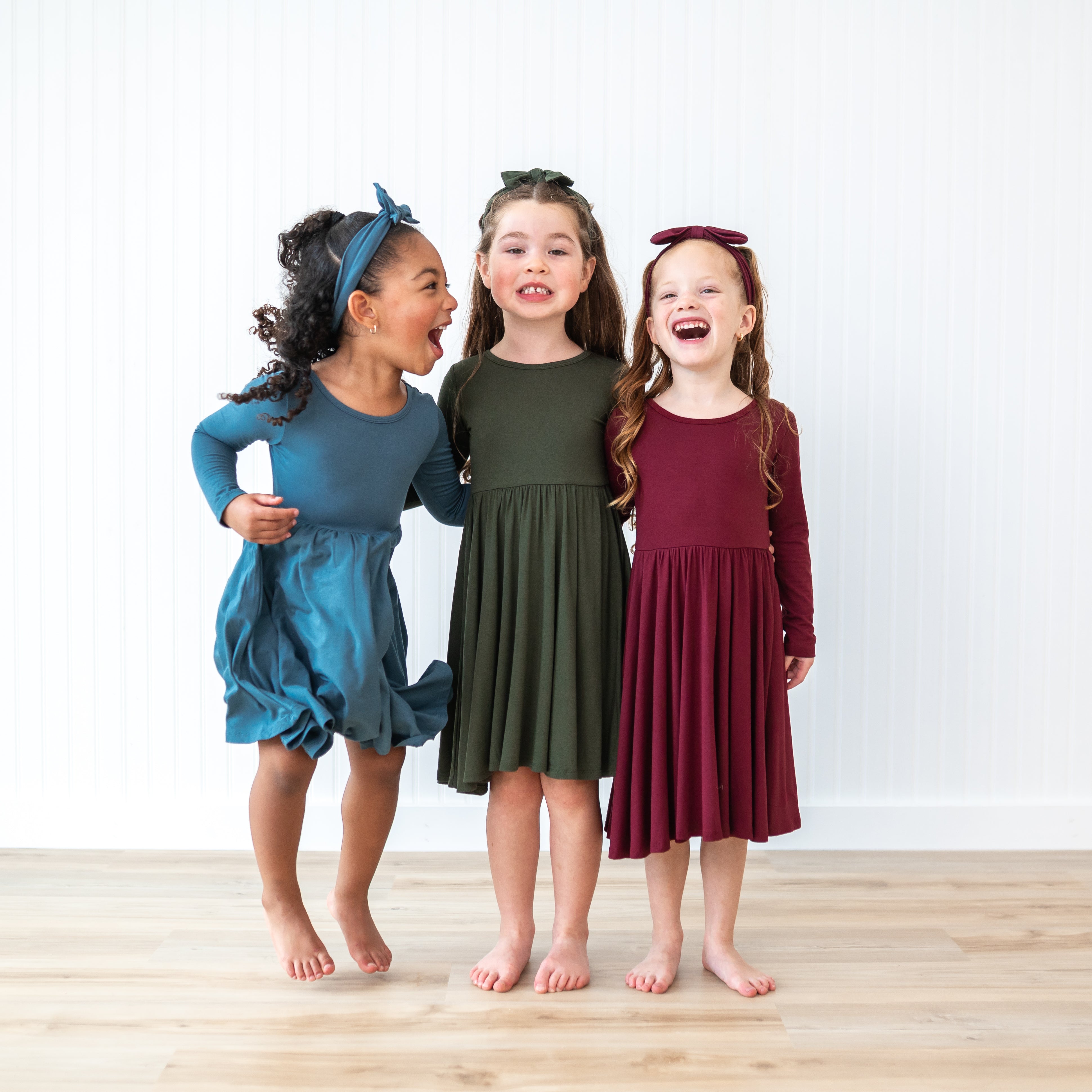 three girls standing together wearing the Long Sleeve Twirl Dressed in Burgundy, Fir and Atlantic