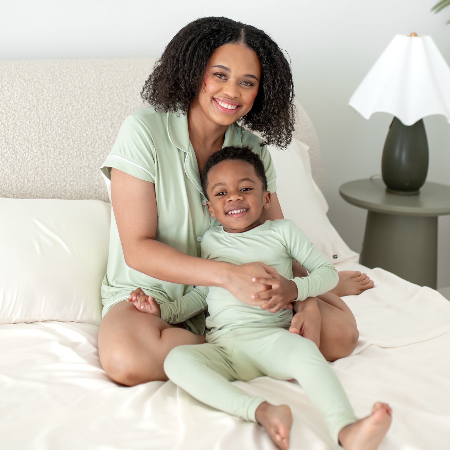 Woman and child wearing mommy and me matching light green pajamas in a bedroom setting