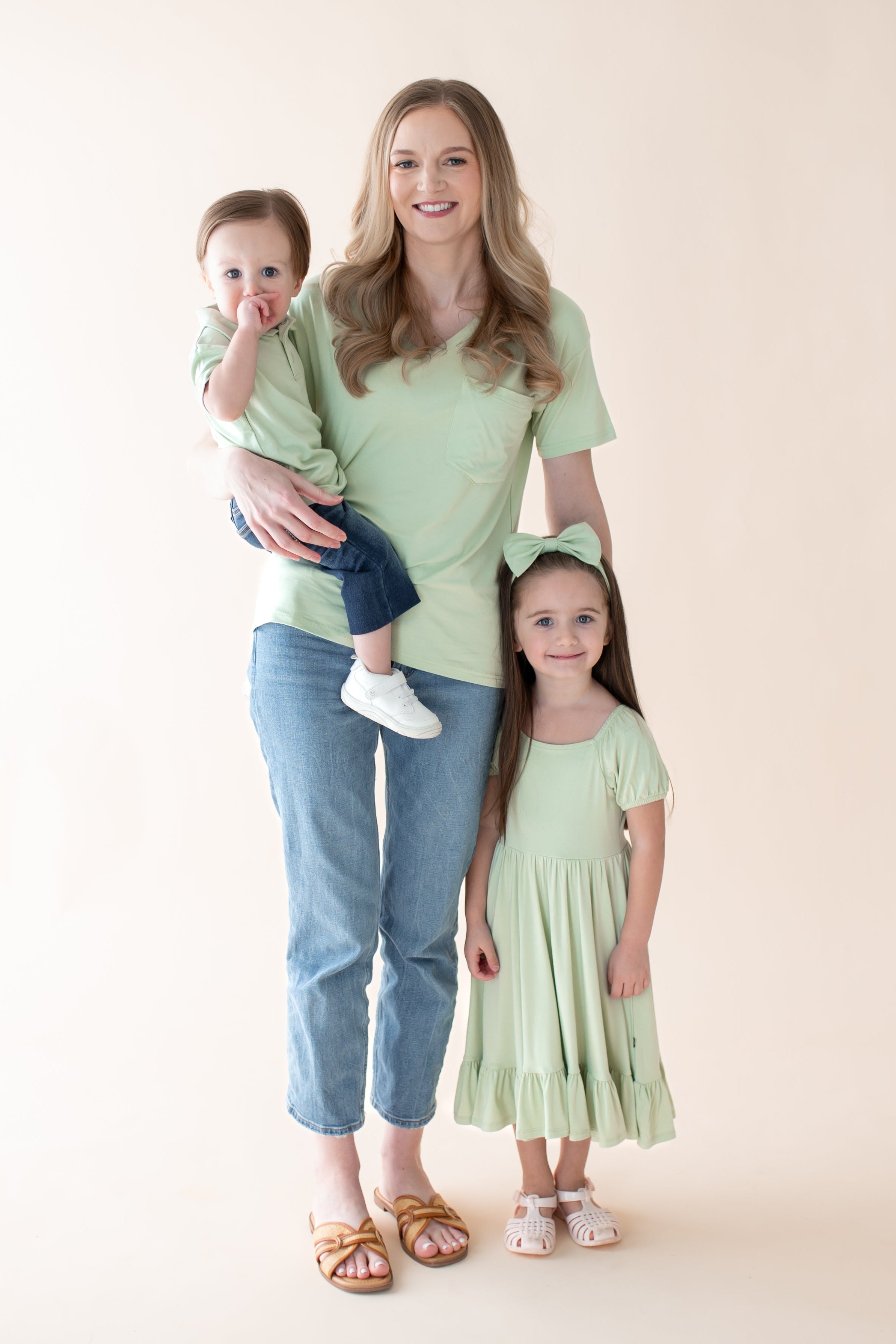 Woman wearing a light green v-neck tee with 2 children in matching green outfits