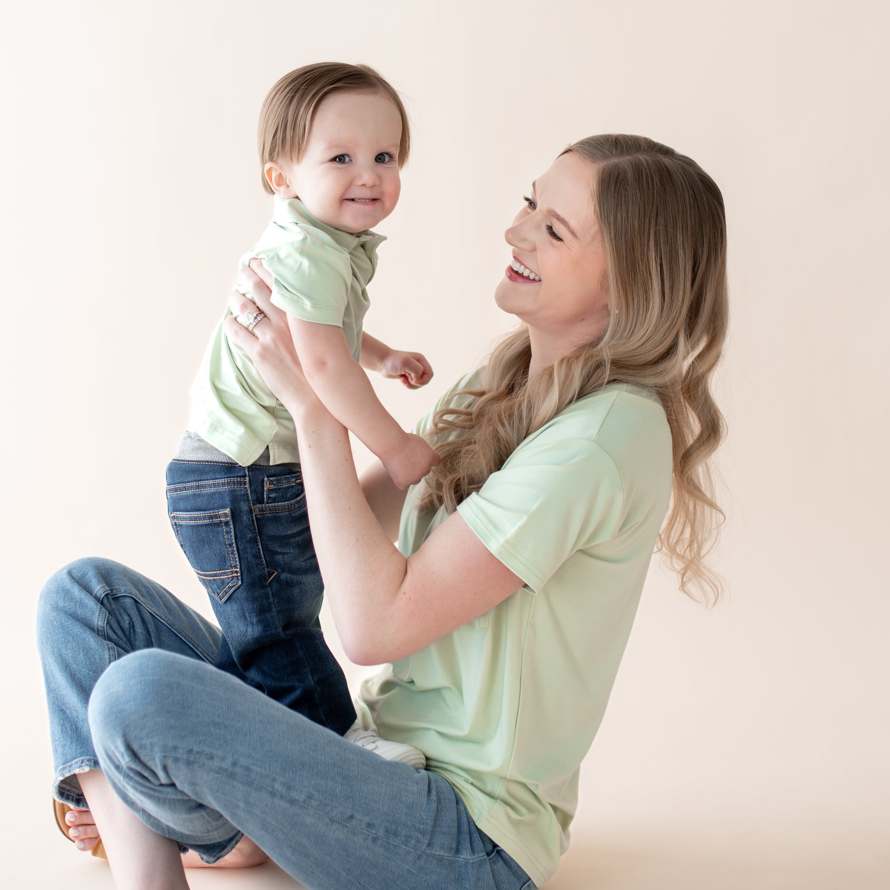 Woman holding a baby and smiling at each other against a plain background