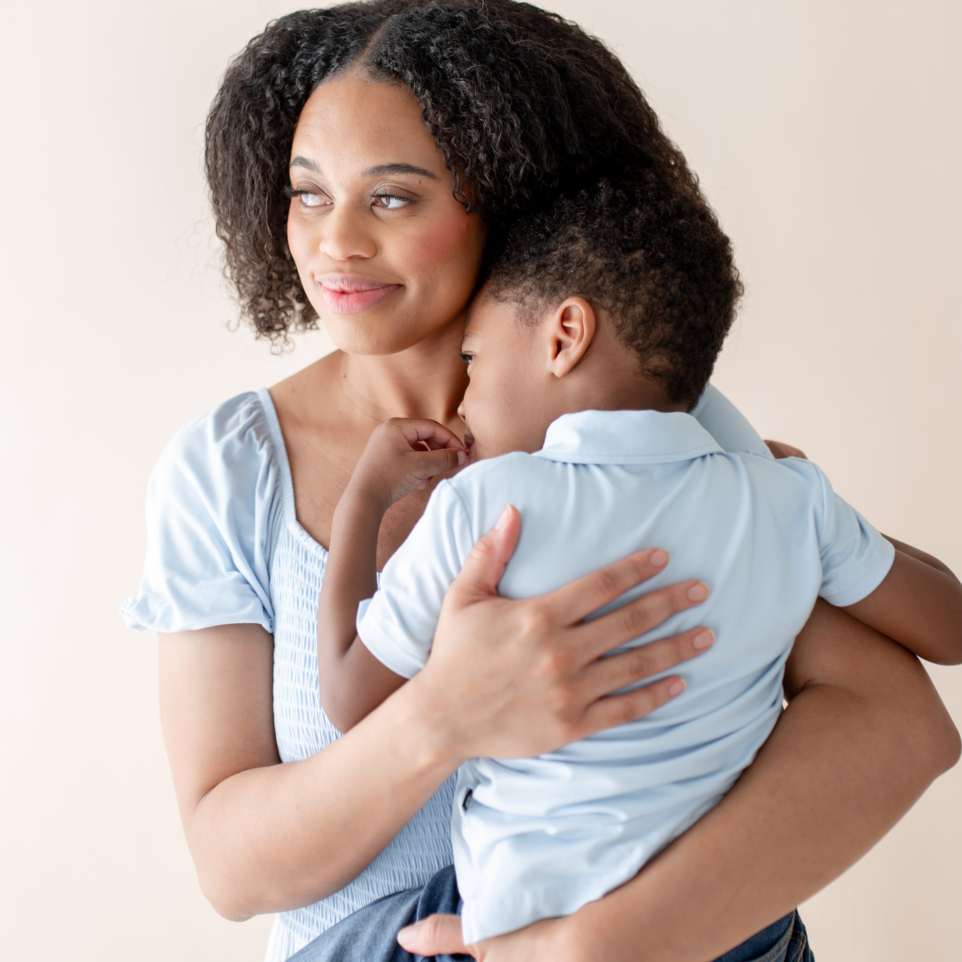 Woman holding a child against a plain background