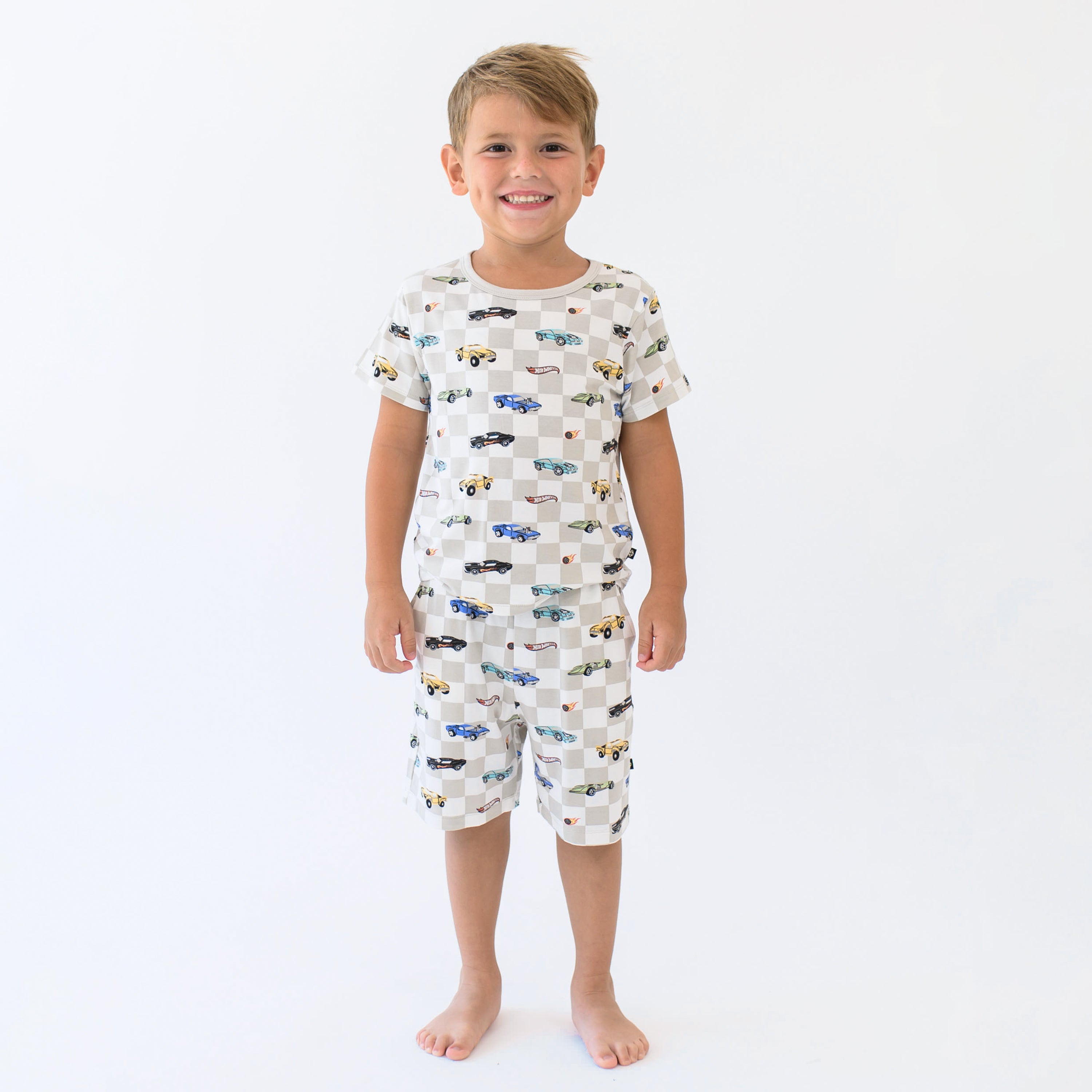Smiling boy wearing the Short Sleeve Pajamas in Fast and Fierce in front of a cream background