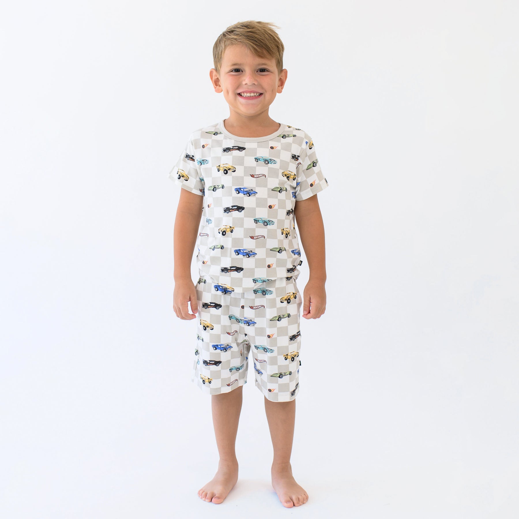 Smiling boy wearing the Short Sleeve Pajamas in Fast and Fierce in front of a cream background