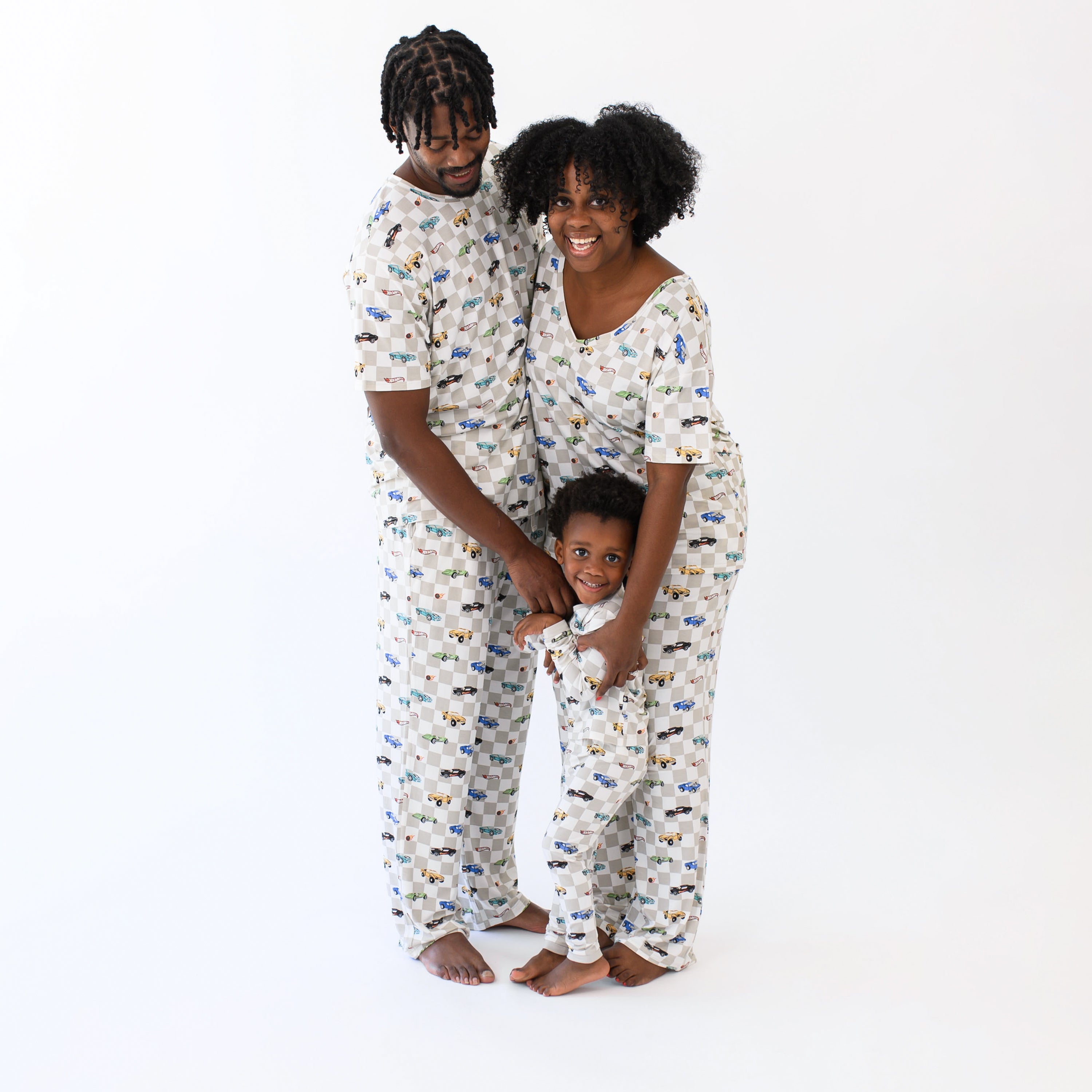 Family matching in Fast and Fierce. Child standing in front of both parents while wife and husband are leaning on one another. Pictured are the Men's Lounge Pants in Fast and Fierce, and Men's Crew neck tee, women's v-neck, women's lounge pants and toddler long sleeve pajamas