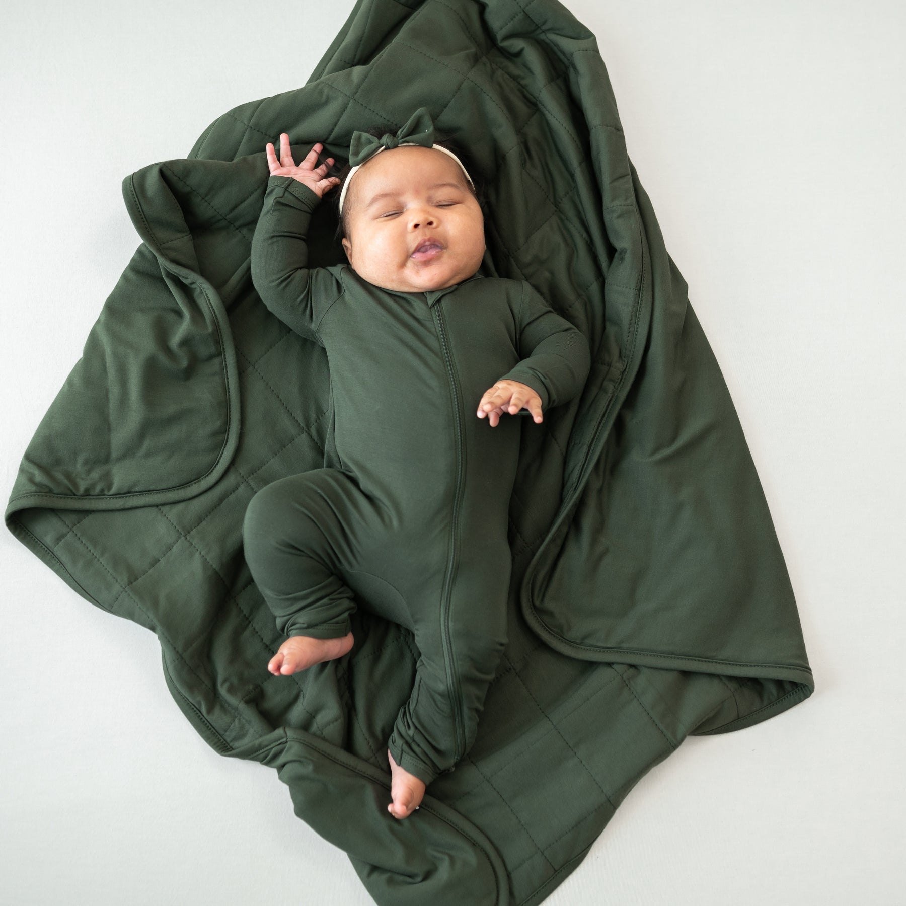 Baby wearing Fir Zippered Romper laying on Baby Blanket in Fir 1.0