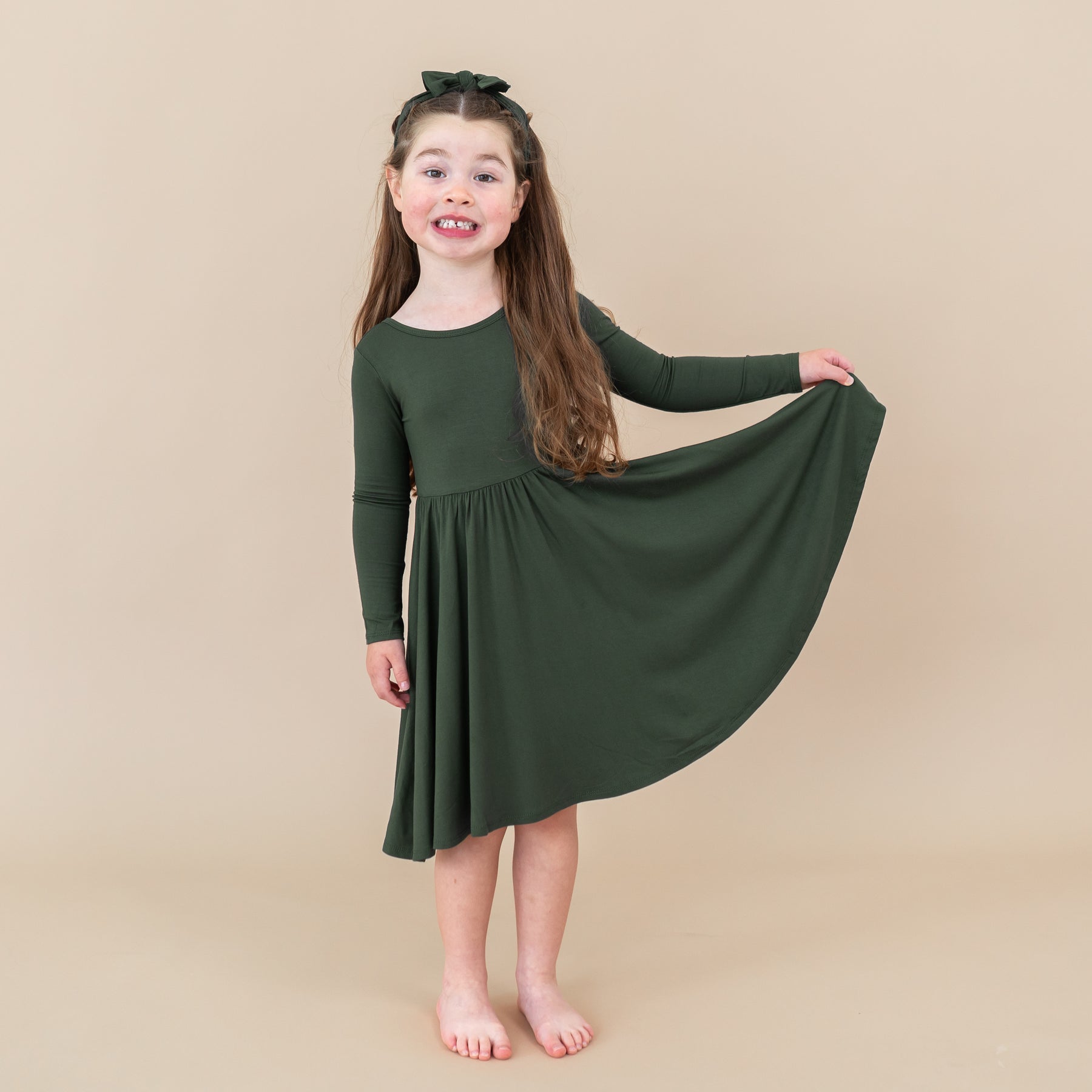 Young girl wearing a green dress against a beige background