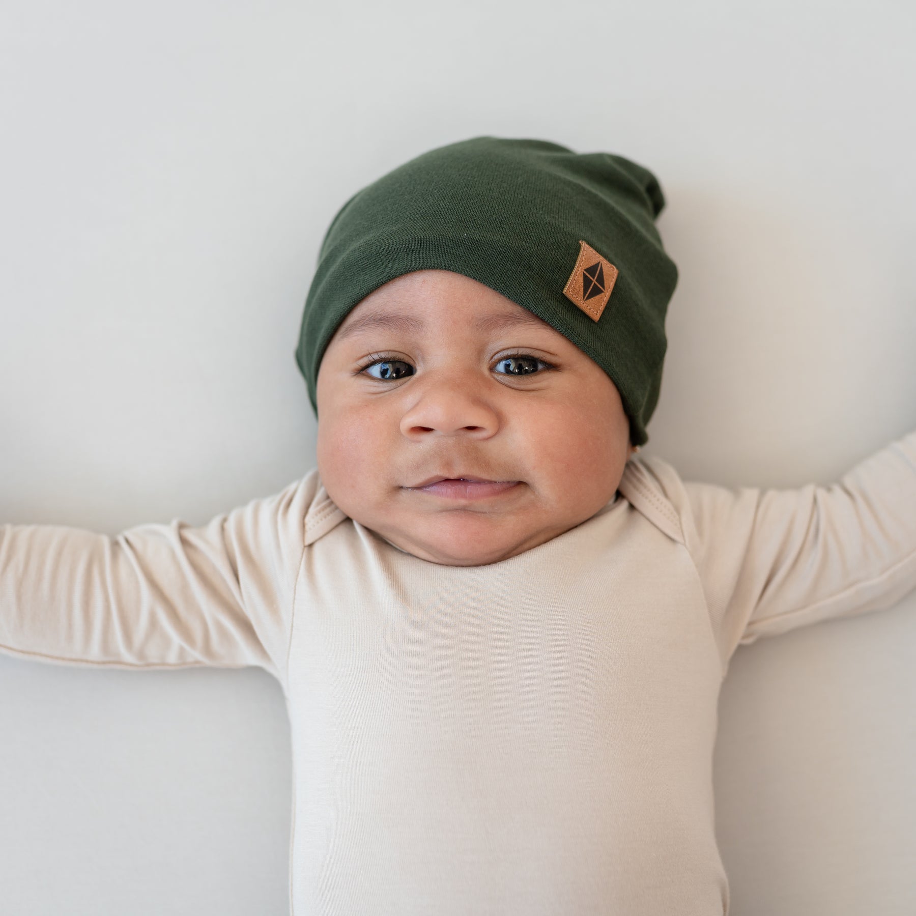 Baby wearing Bamboo Jersey Beanie in Fir with Bisque long sleeve bodysuit
