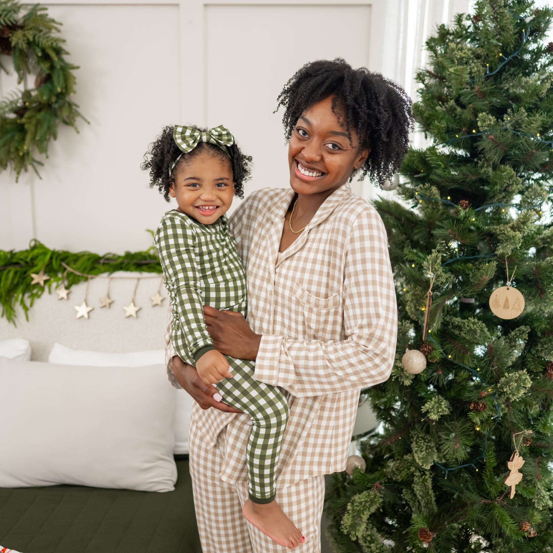 Mother wearing the Long-Sleeved Women's Pajama Set in Gingham Bisque holding daughter wearing the Long sleeve Toddler Pajama Set in Fir Gingham