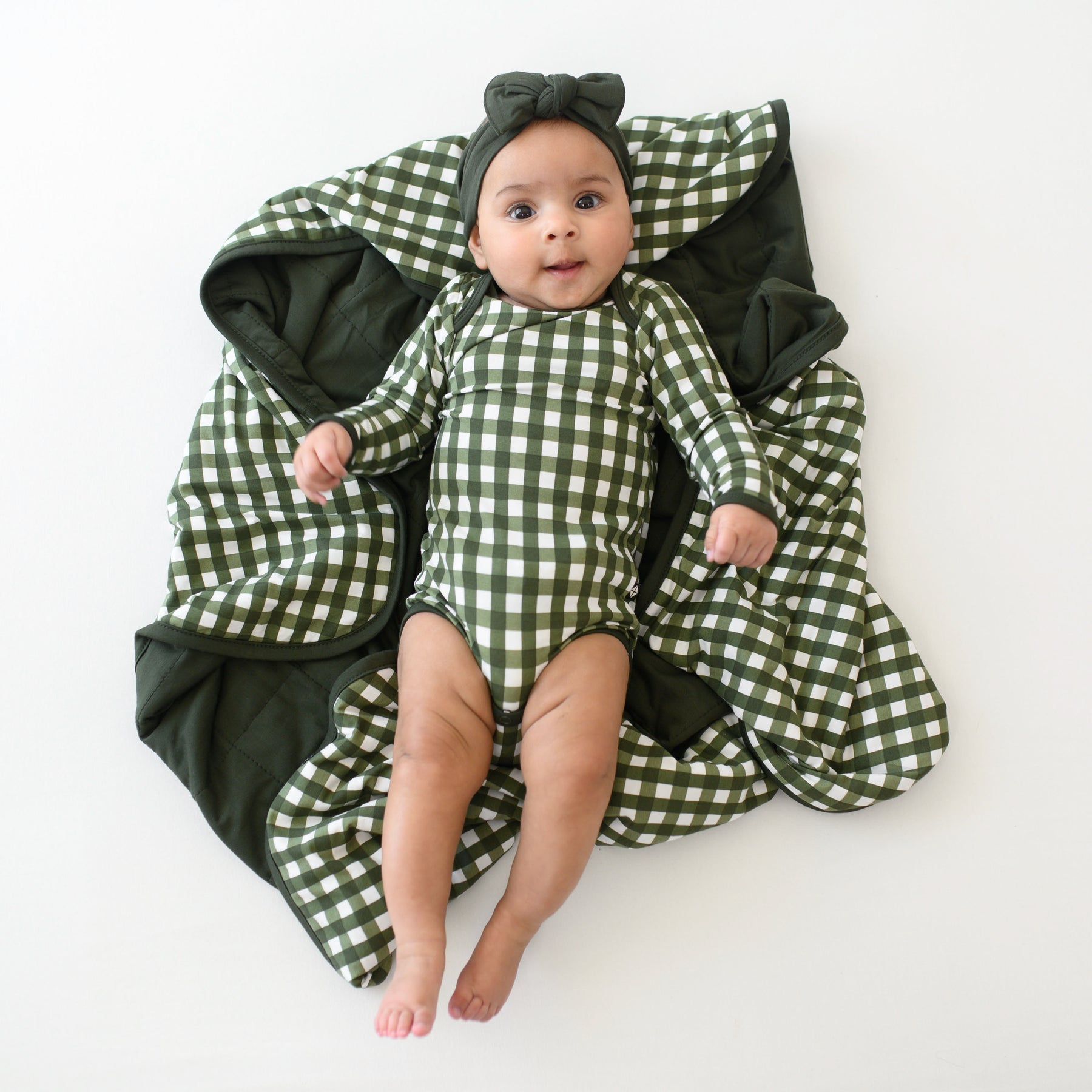 Infant laying on a Baby Blanket in Gingham Fir wearing a matching long sleeve bodysuit