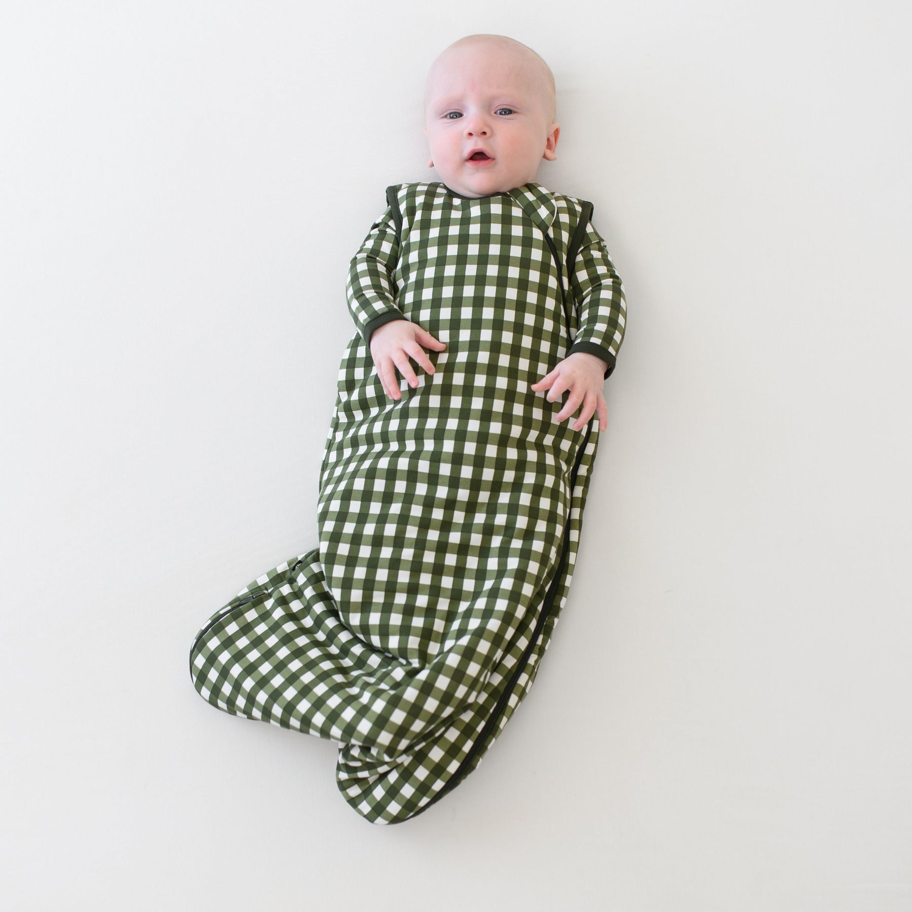 Baby wearing Sleep Bag in Gingham Fir 1.0 over green gingham pajamas