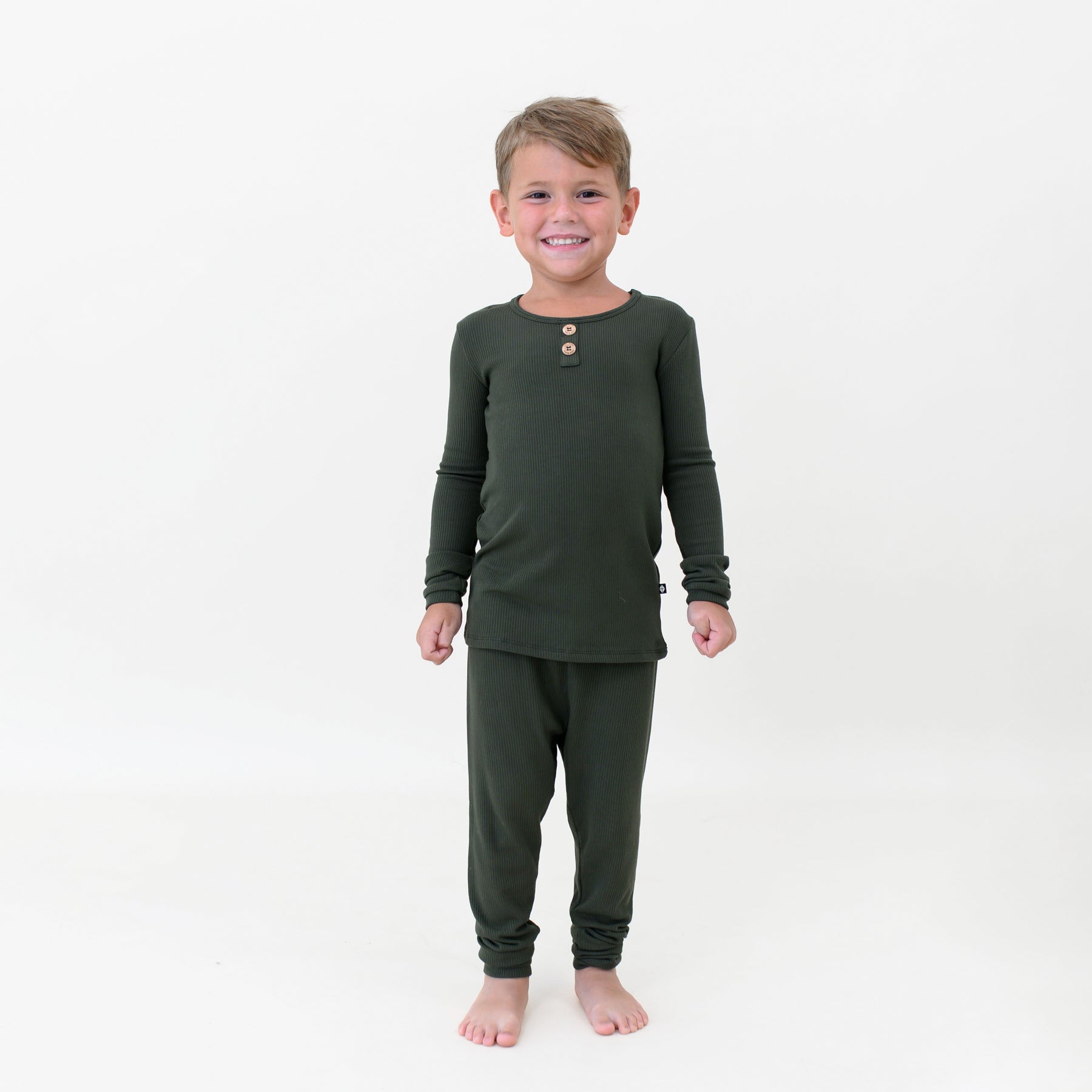 Young boy wearing the Ribbed Henley Set in Fir in front of a white colored backdrop