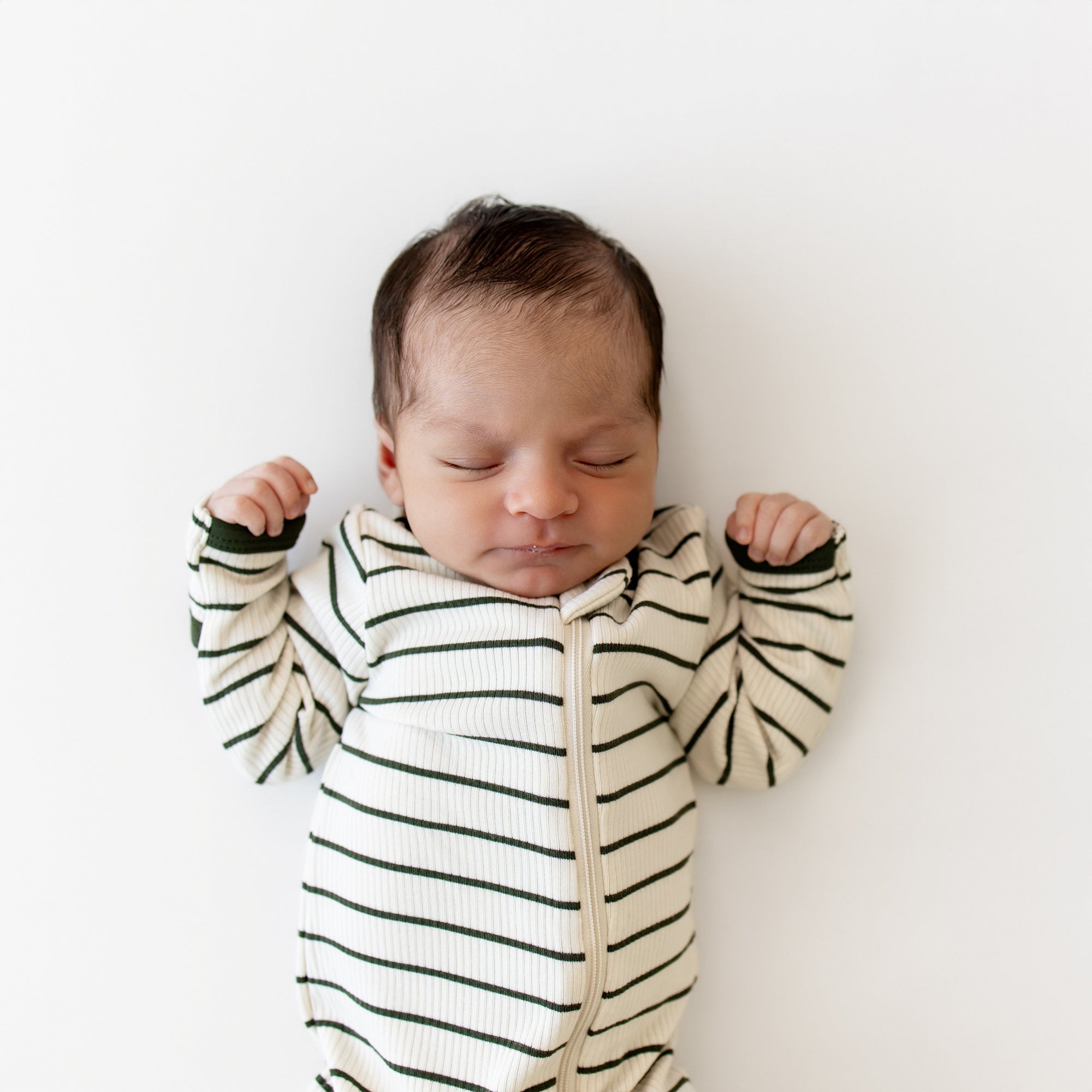 Close up of sleeping newborn wearing the Ribbed Zipper Footie in Fir Stripe