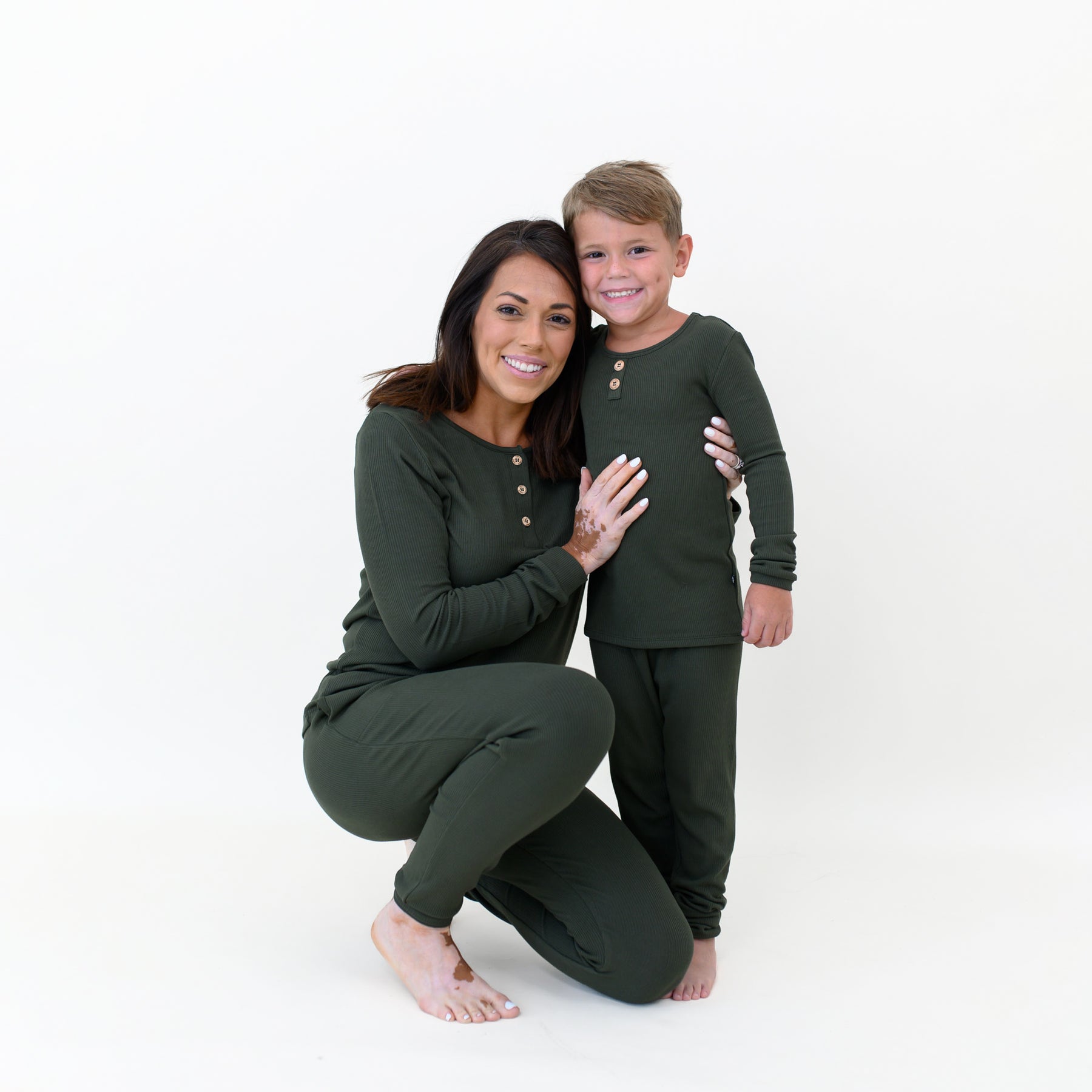 Mother kneeling beside son with her arms around him both matching in the Ribbed Henley Sets in Fir
