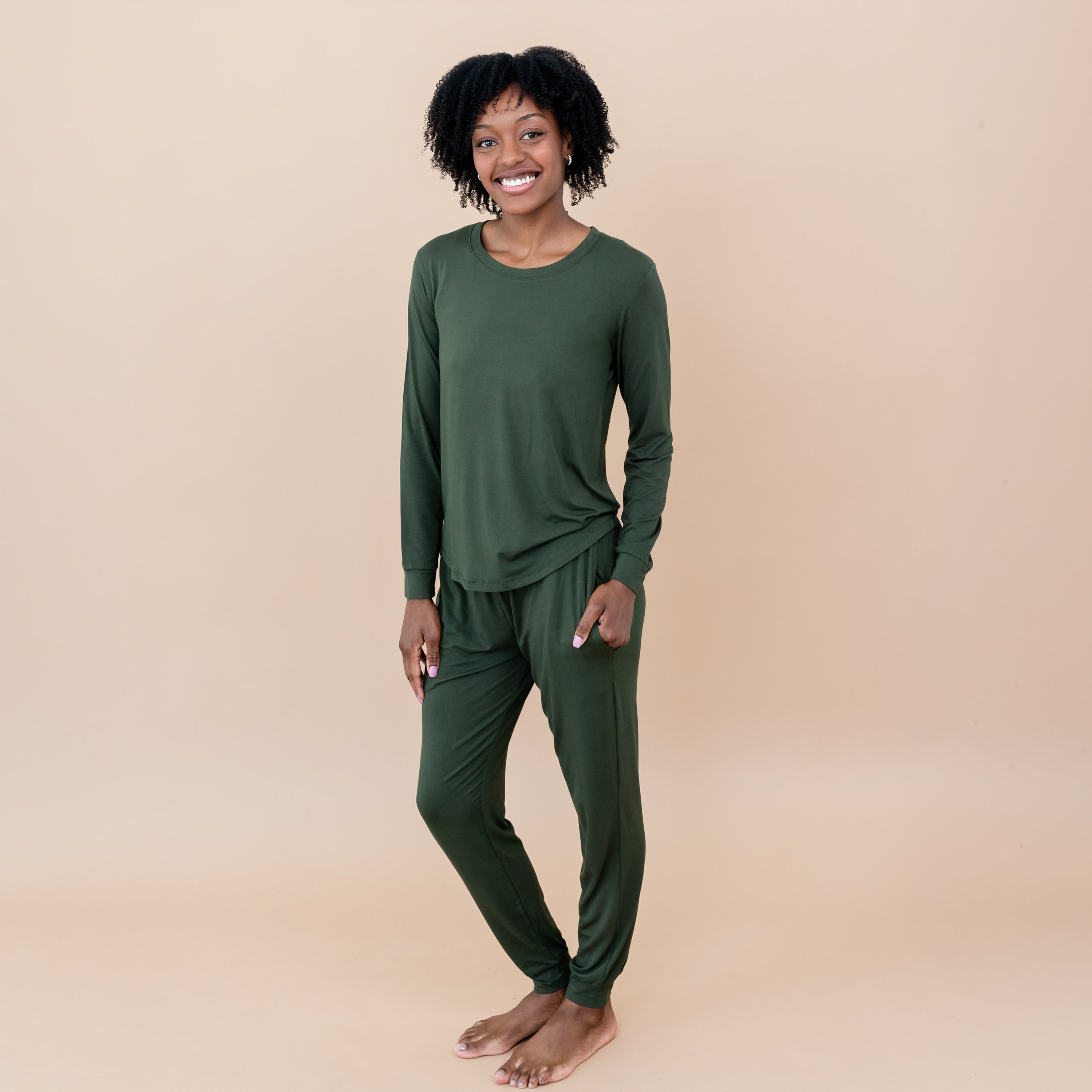 Woman wearing a green pair of bamboo pajamas on a beige background