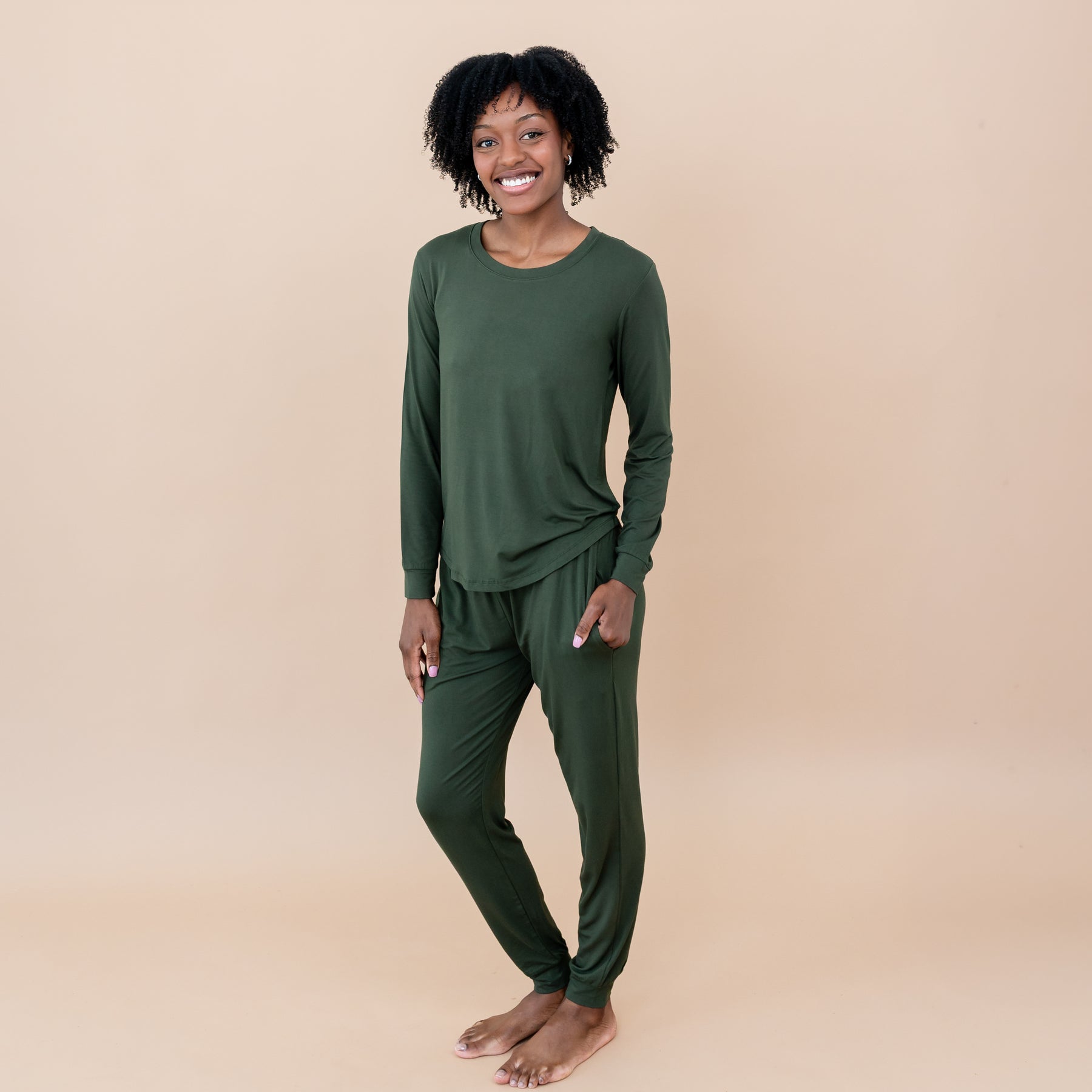Woman wearing a green pair of bamboo pajamas on a beige background