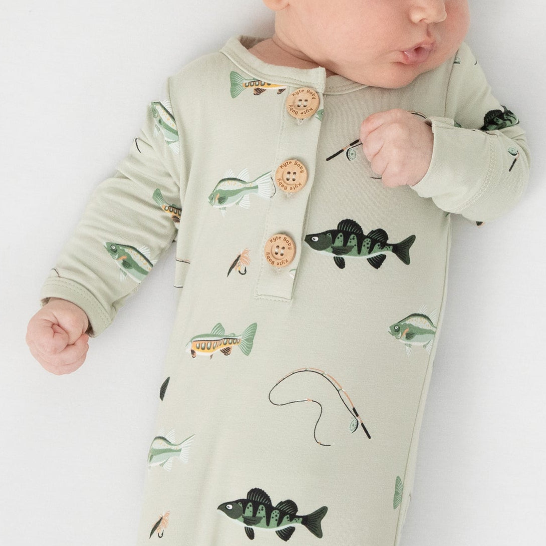newborn laying on a white blanket wearing the Knotted Gown with Hat Set in Fishing tied at the bottom