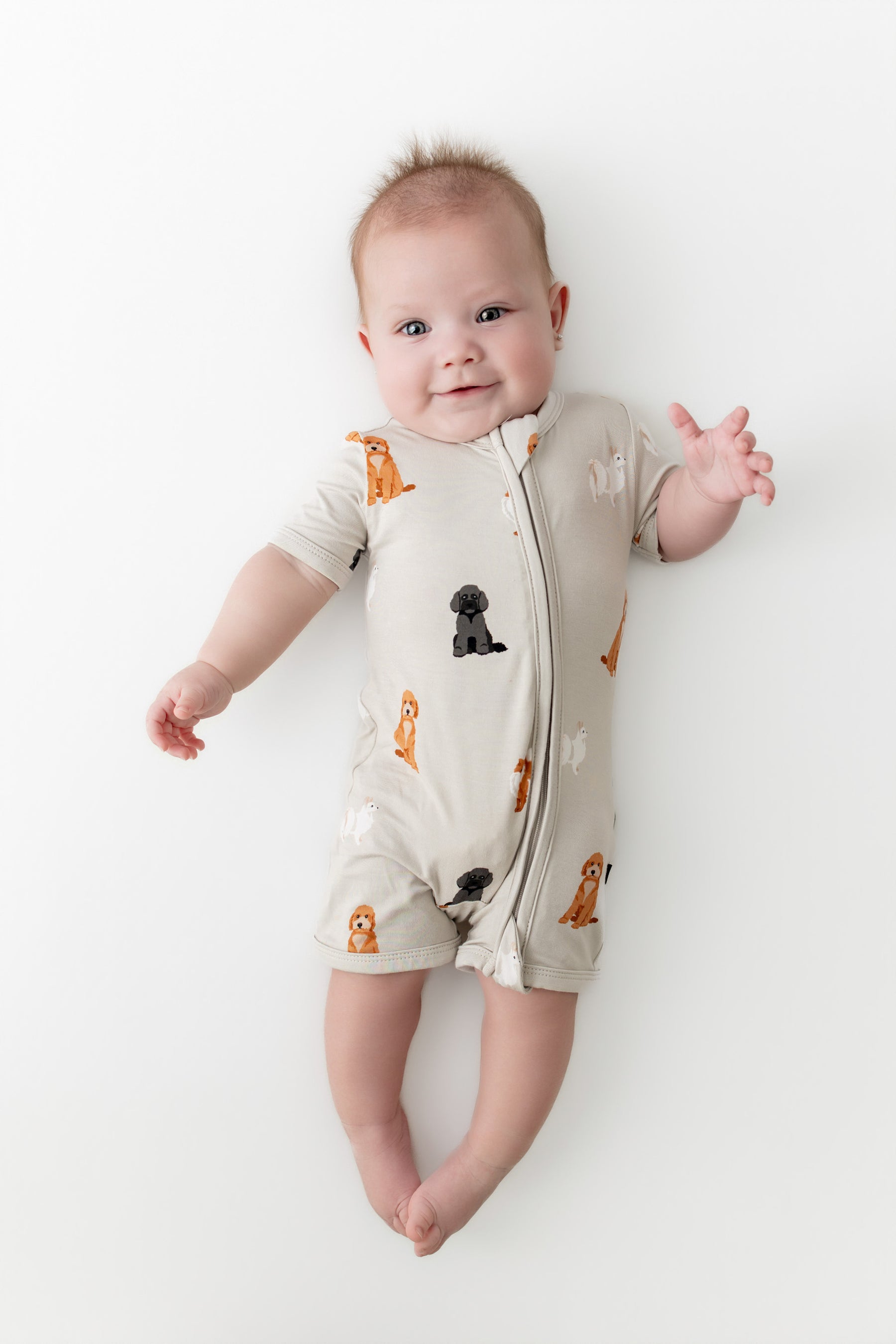 Baby wearing a onesie with dog prints on a white background