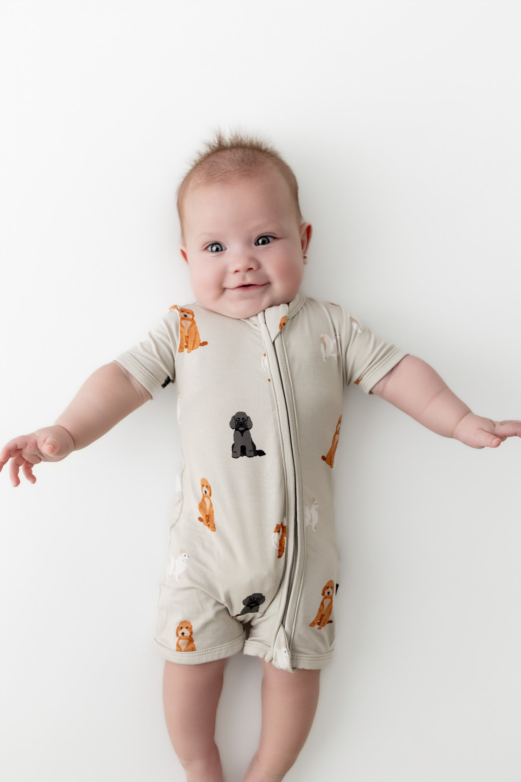 Baby wearing a  dog patterned onesie on a white background
