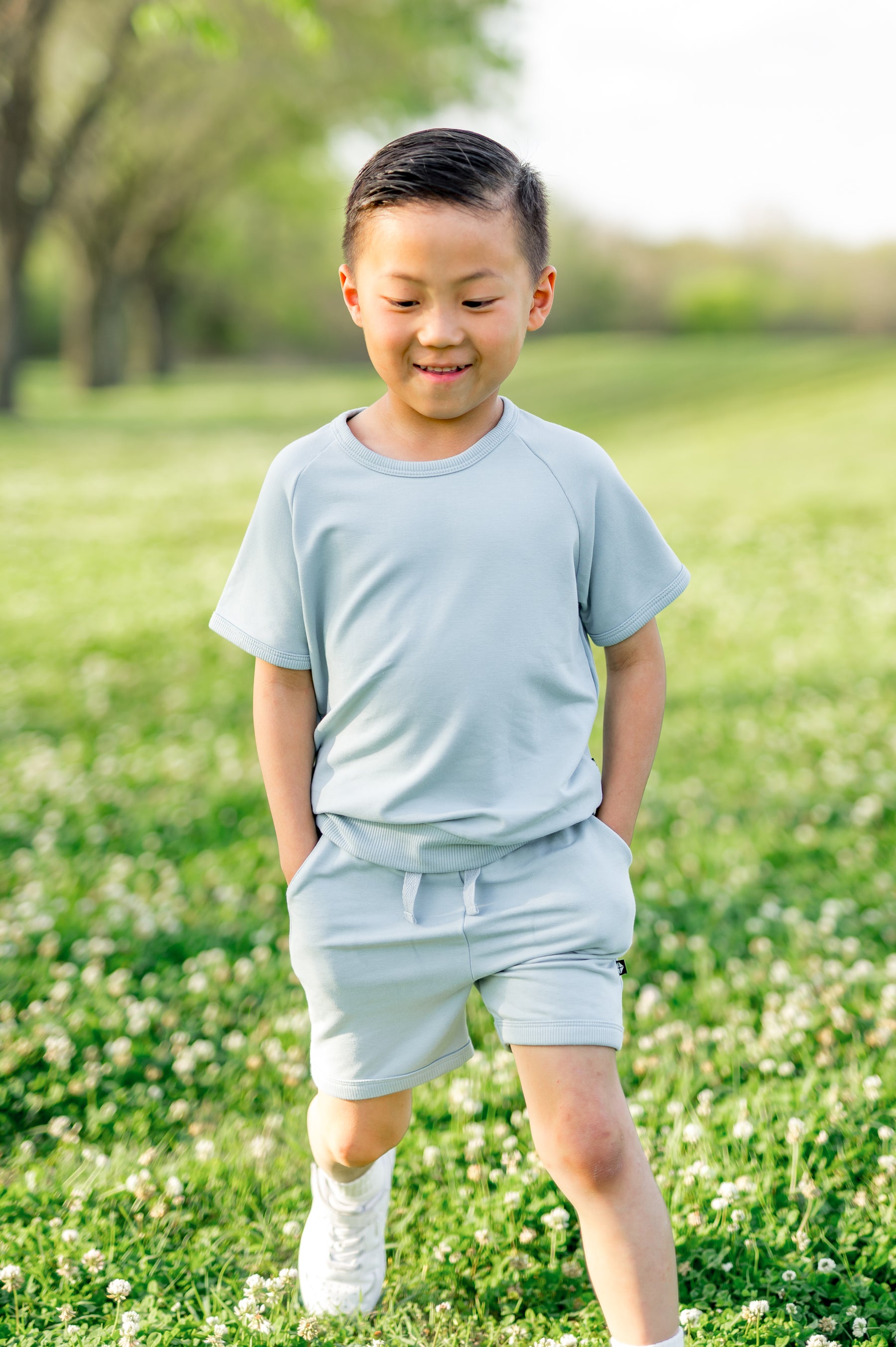 Young boy walking wearing the Short Sleeve Jogger Set in Fog with his hands in the shorts pocket