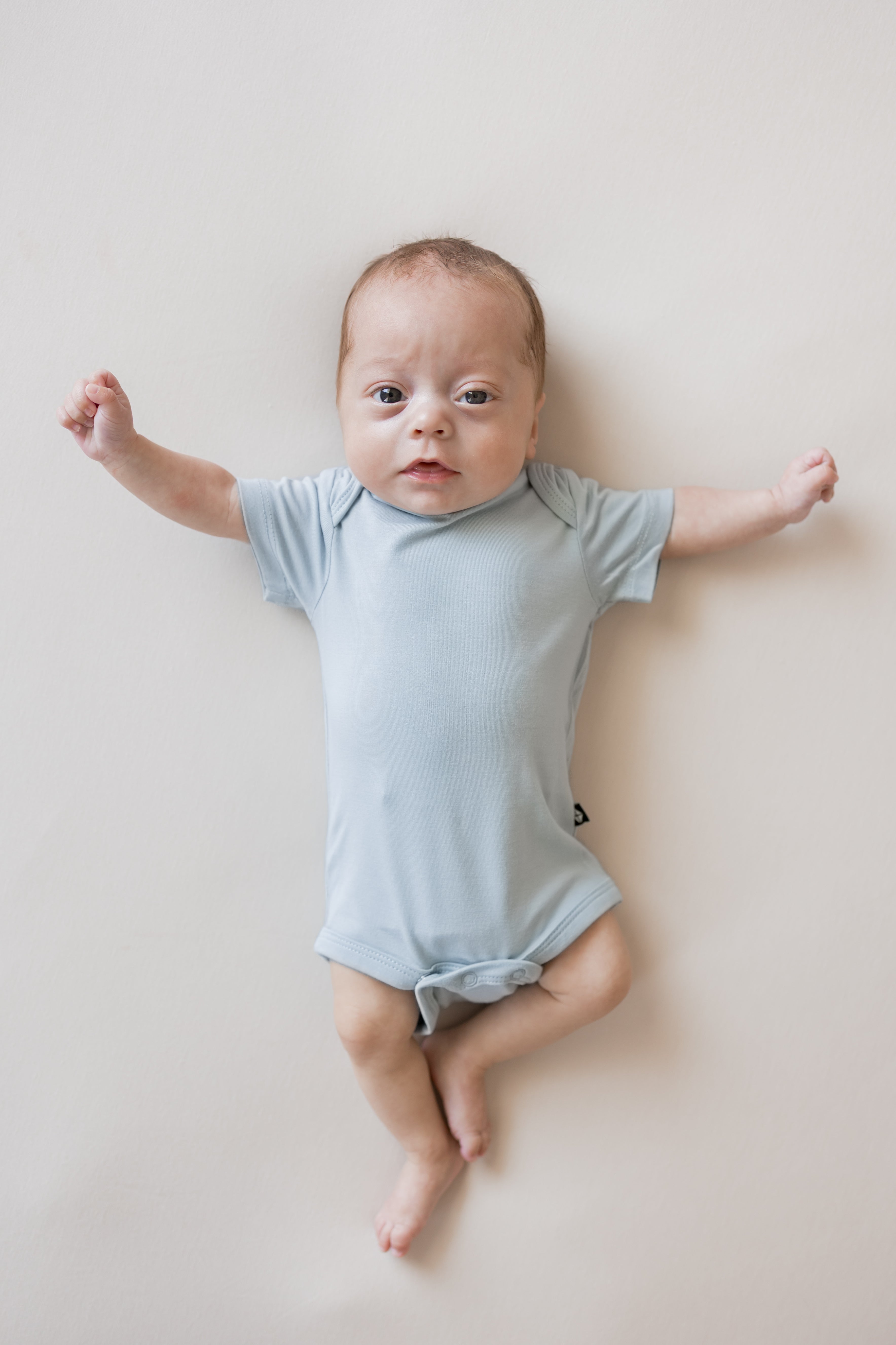 Baby wearing Bodysuit in Fog color on a beige background