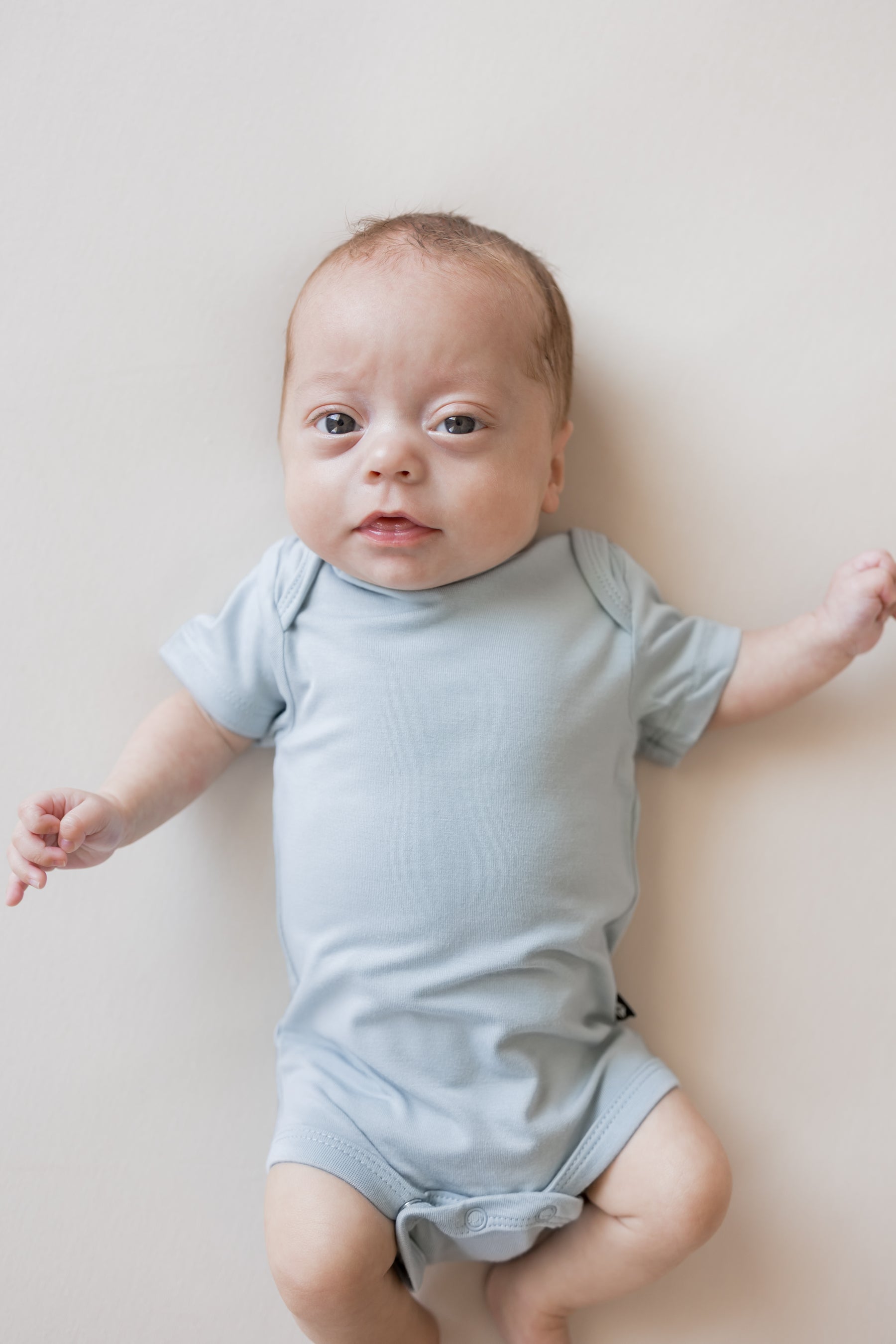 Close up of Baby wearing Bodysuit in Fog color on a beige background