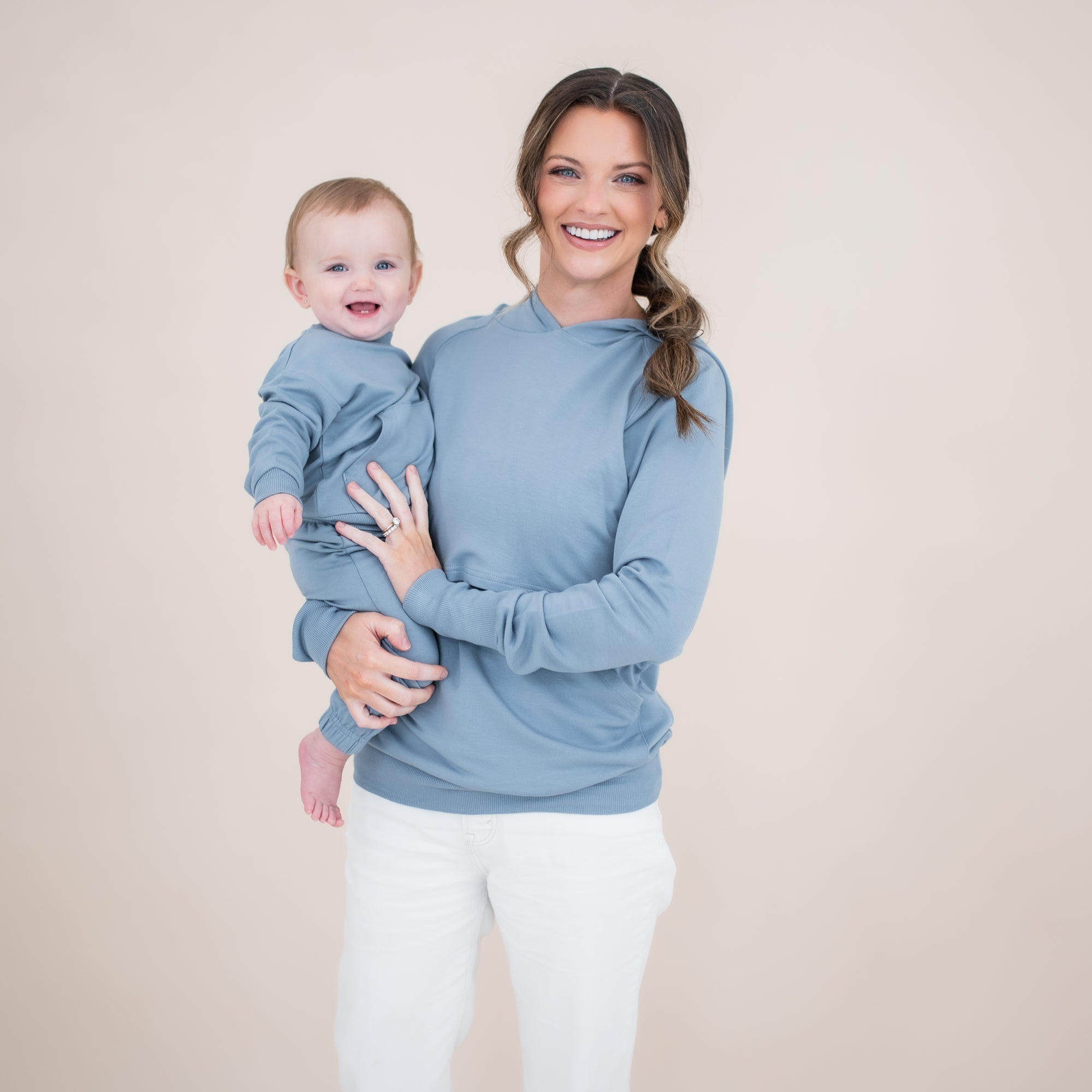 Smiling mother holding her smiling toddler both matching in Slate. Young child wearing the French Terry Jogger Set in Slate with mother wearing the French Terry Nursing hoodie