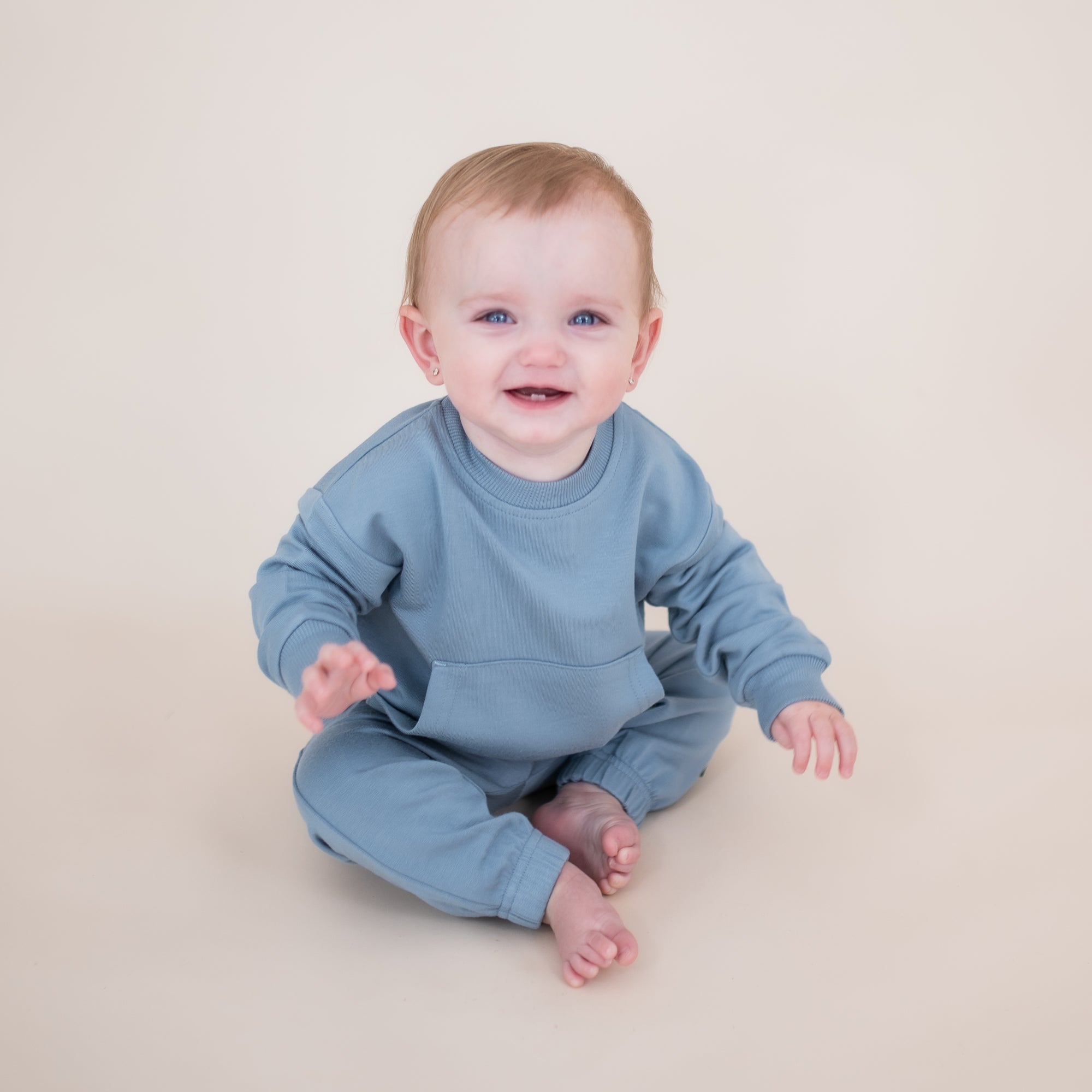 Young smiling toddler sitting on the floor wearing the French Terry Jogger Set in Slate