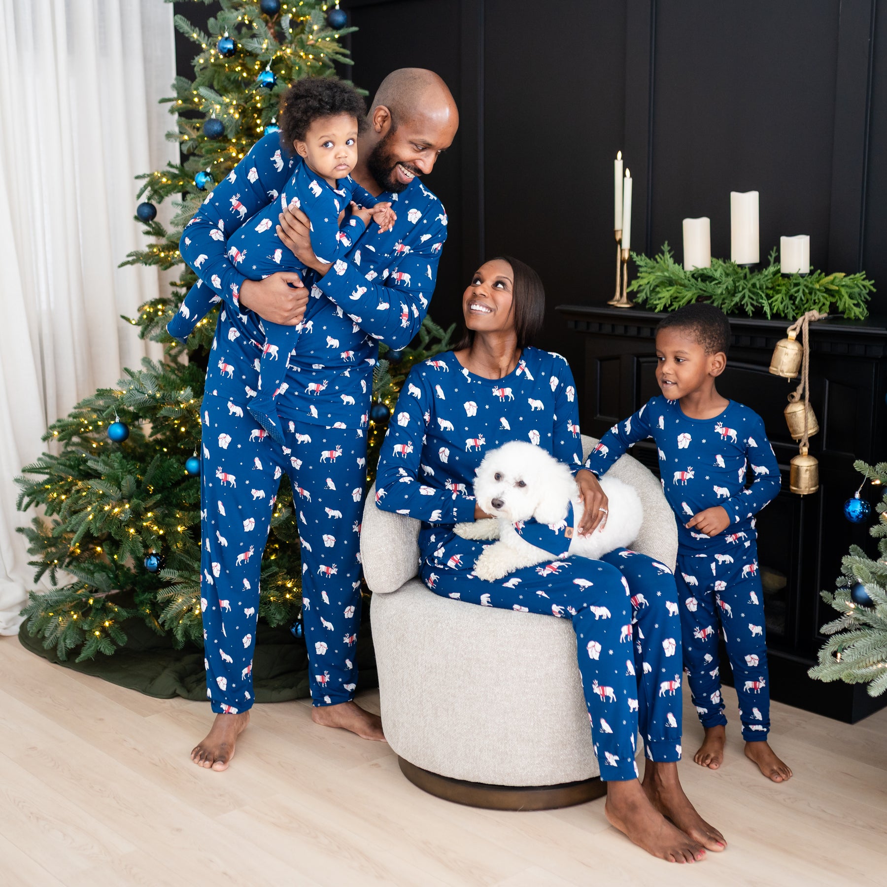 Family of four matching in the holiday Print Frosty Friends with white dog sitting on mom's lap wearing the Dog Bandana in Frosty Friends
