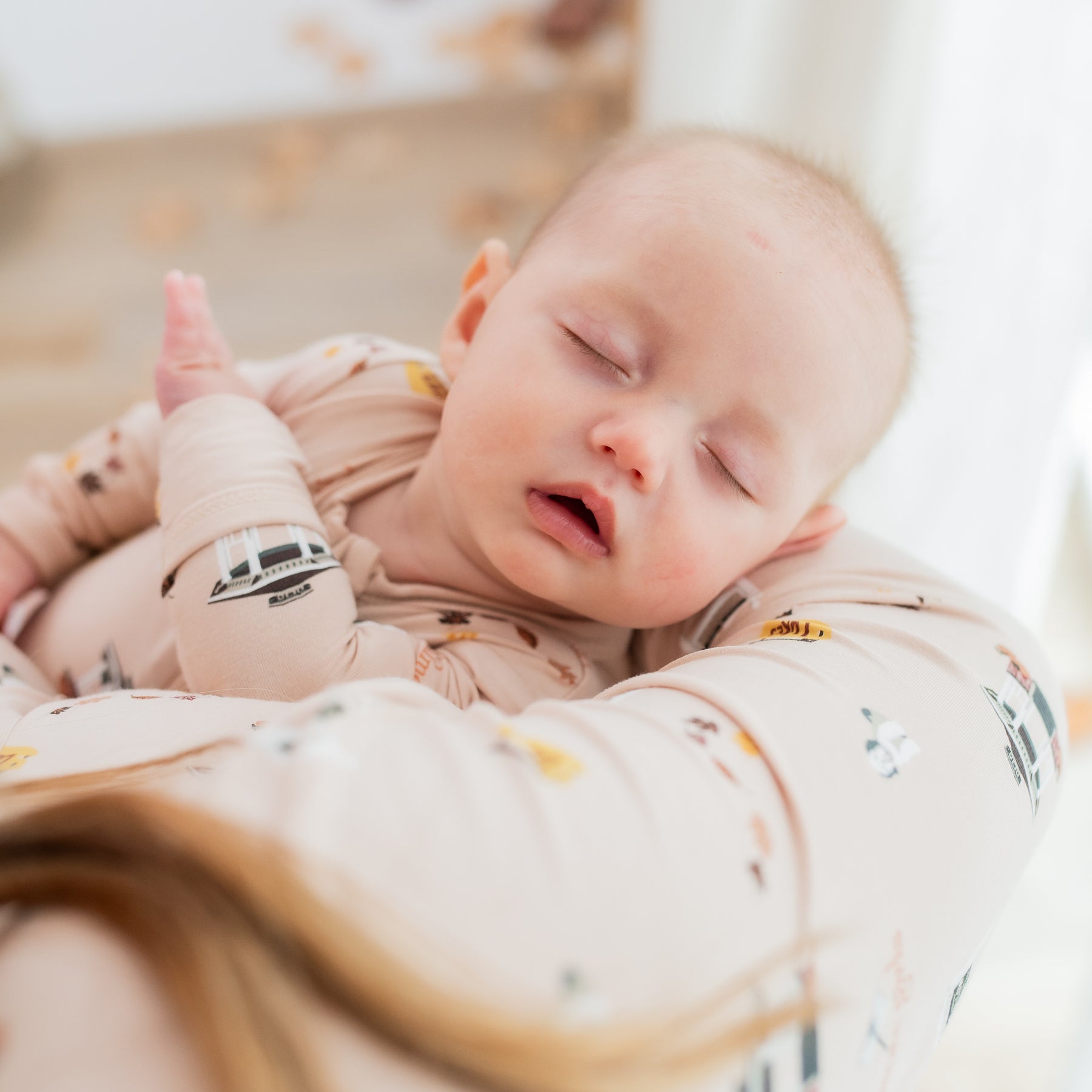 Sleeping infant wearing the Zippered Romper in Gilmore Girls being held by her mother who is wearing a matching women's henley