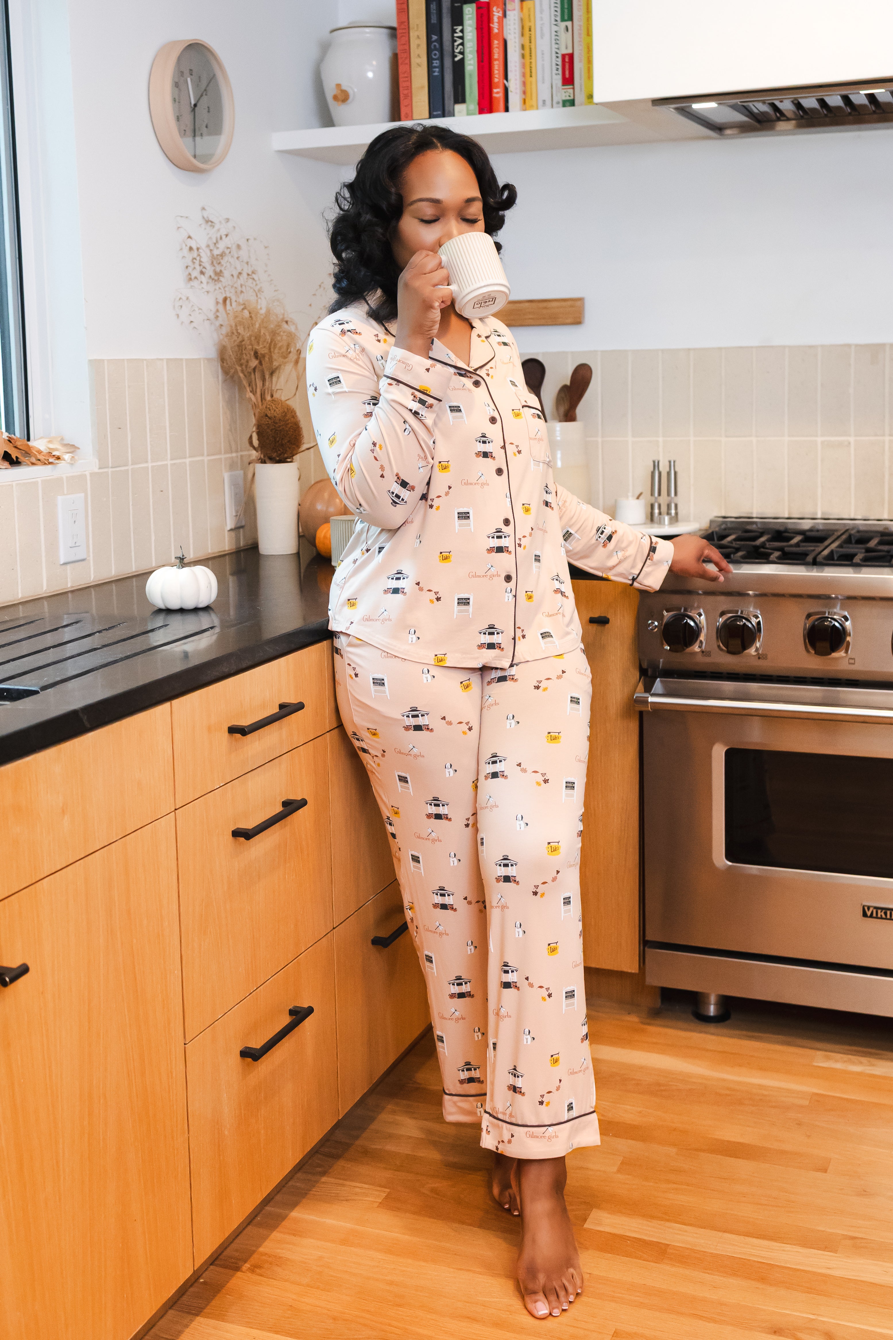 Woman in Gilmore Girls pajamas drinking coffee in a kitchen