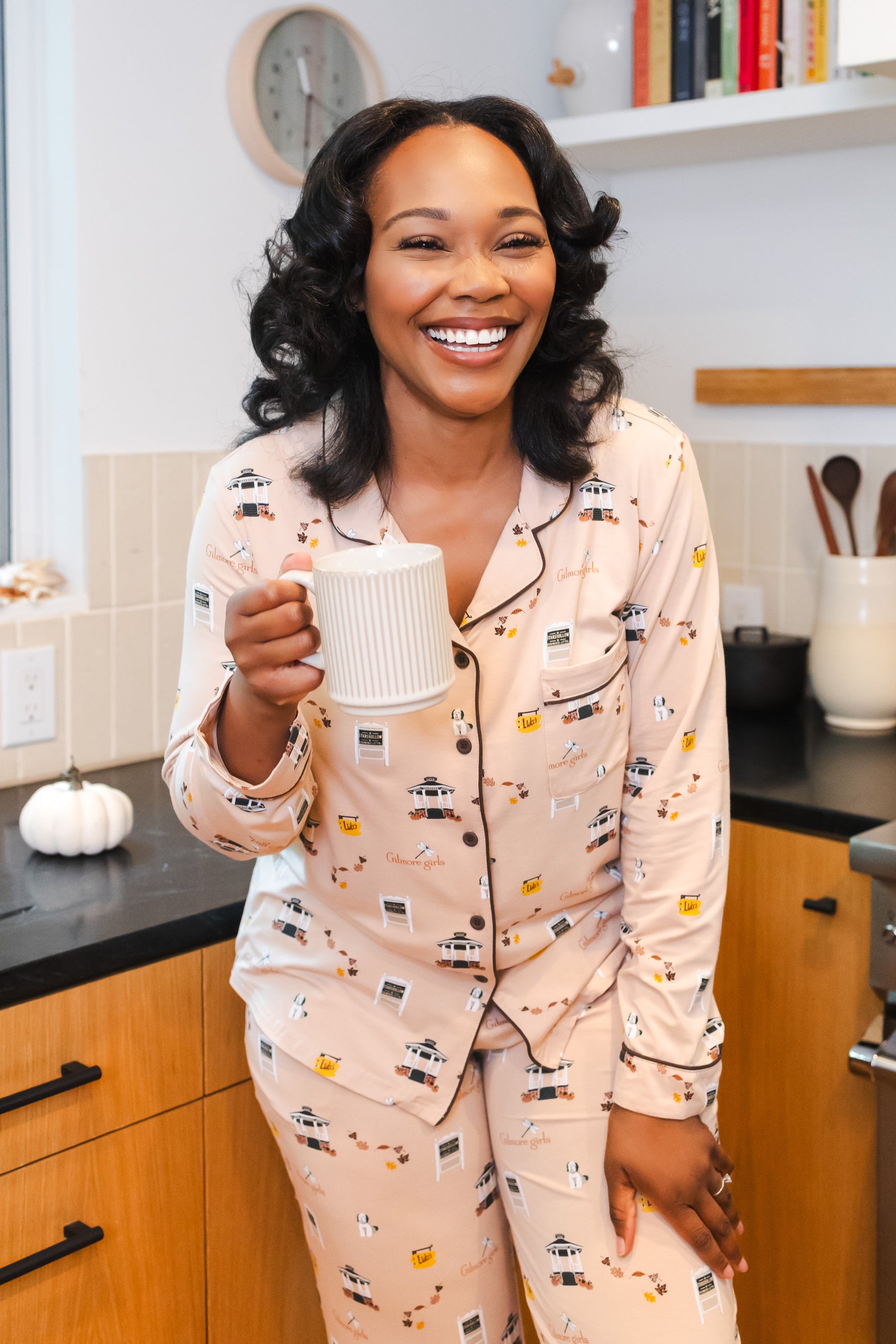 Woman in Gilmore Girls pajamas holding a mug in a kitchen