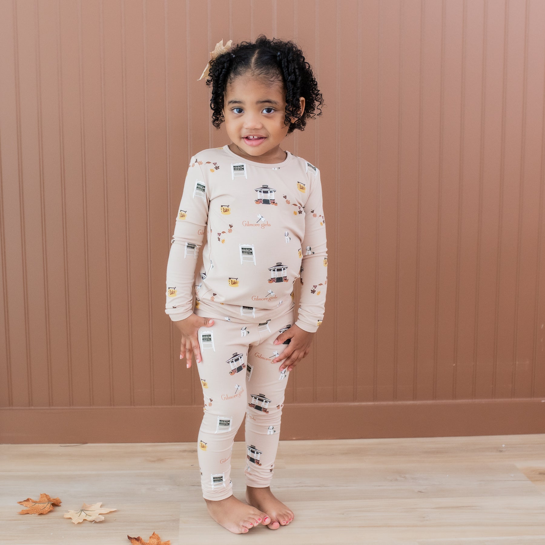 Young girl standing in front of a brown tan paneled wall wearing the Long Sleeve Pajamas in Gilmore Girls
