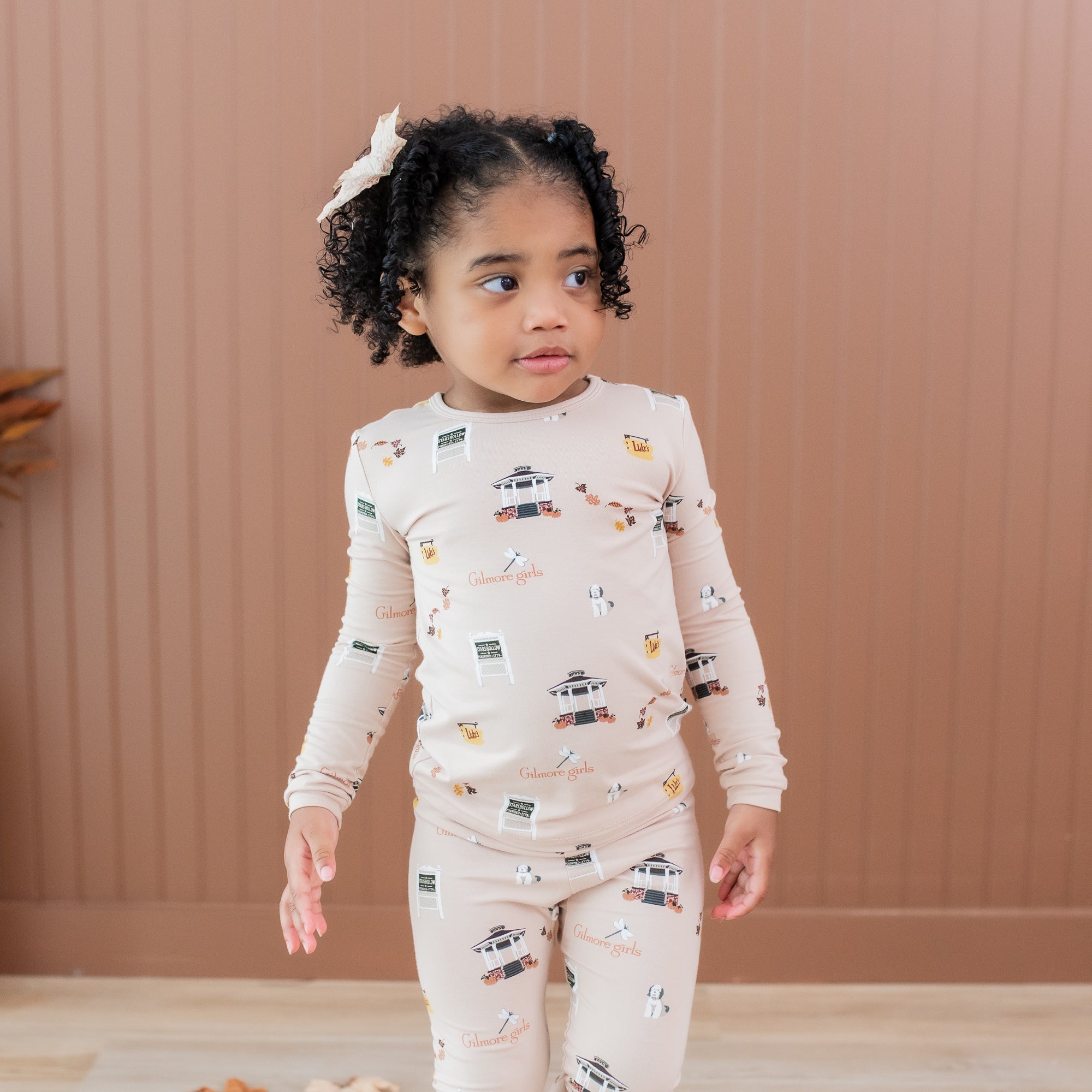 Close up of a young girl wearing the Long Sleeve Pajamas in Gilmore Girls standing in front of a light brown paneled wall