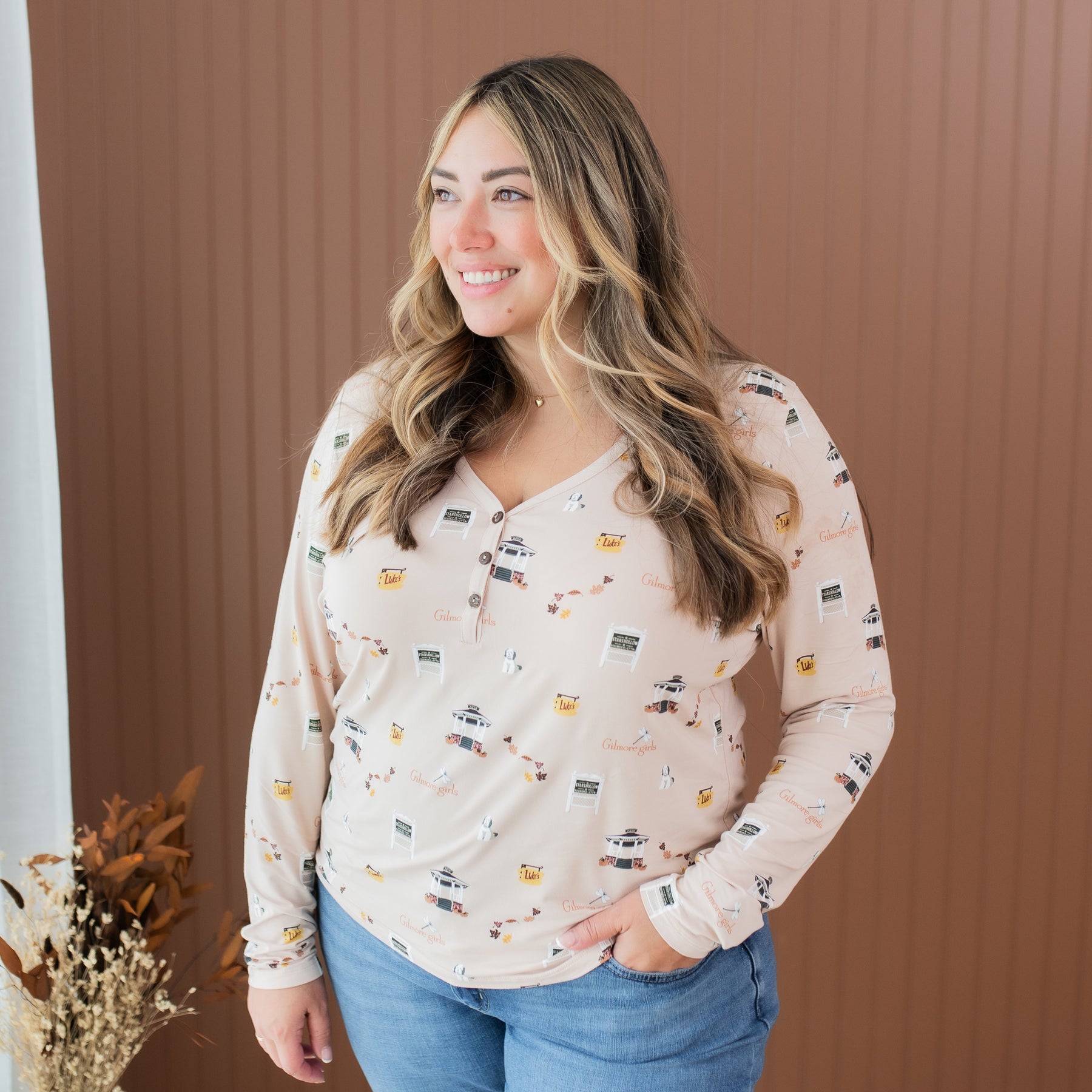 Smiling female model wearing the Women's Long Sleeve Henley Tee in Gilmore Girls with one hand in her jeans pocket