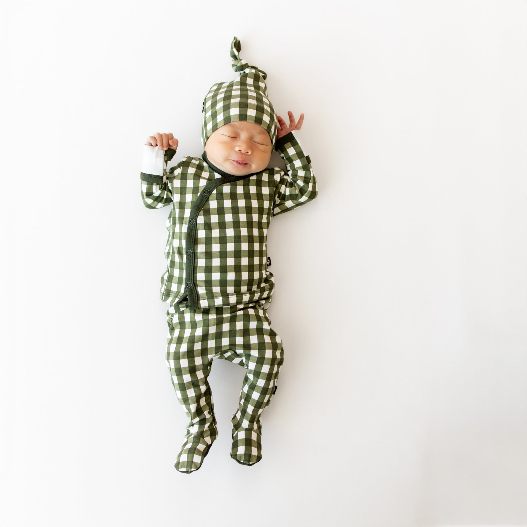 Baby in green and white checkered outfit on a white background