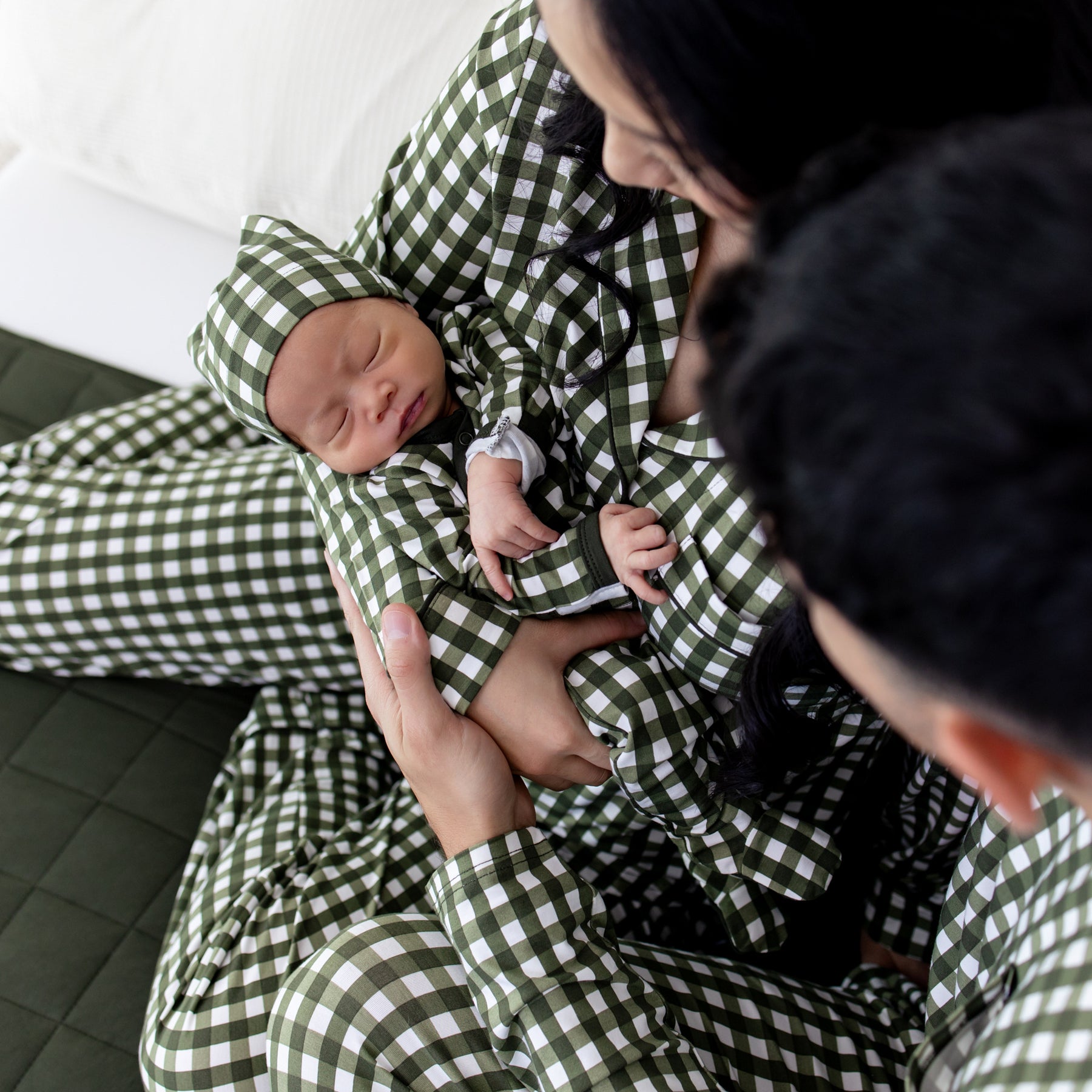 Family of three sitting on a bed all matching in Gingham Fir