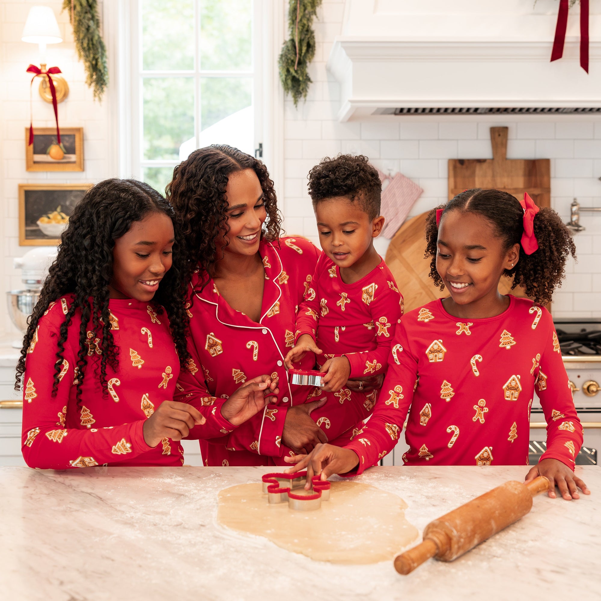 family of 4 in matching christmas gingerbread pajamas in a bright kitchen