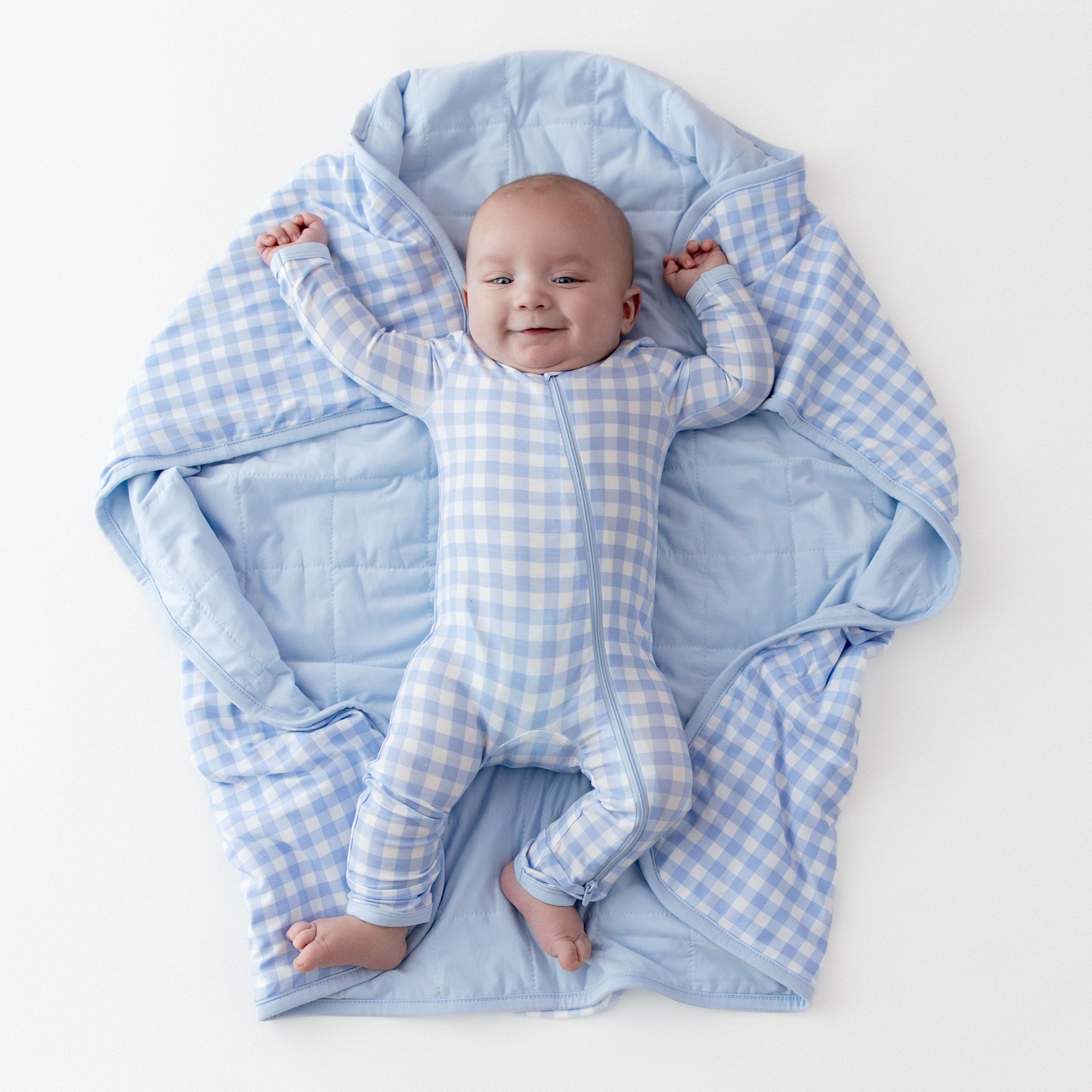 Young infant laying on a Baby Blanket in Gingham Breeze wearing a matching zippered romper