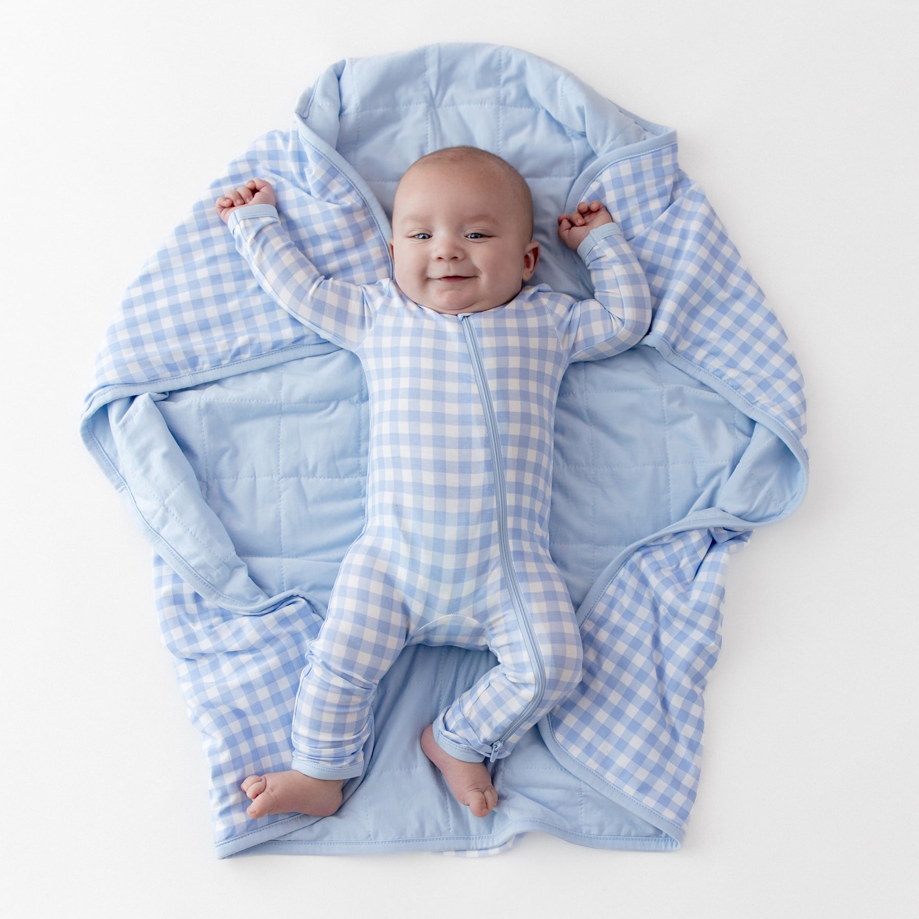 Young infant laying on a Baby Blanket in Gingham Breeze wearing a matching zippered romper