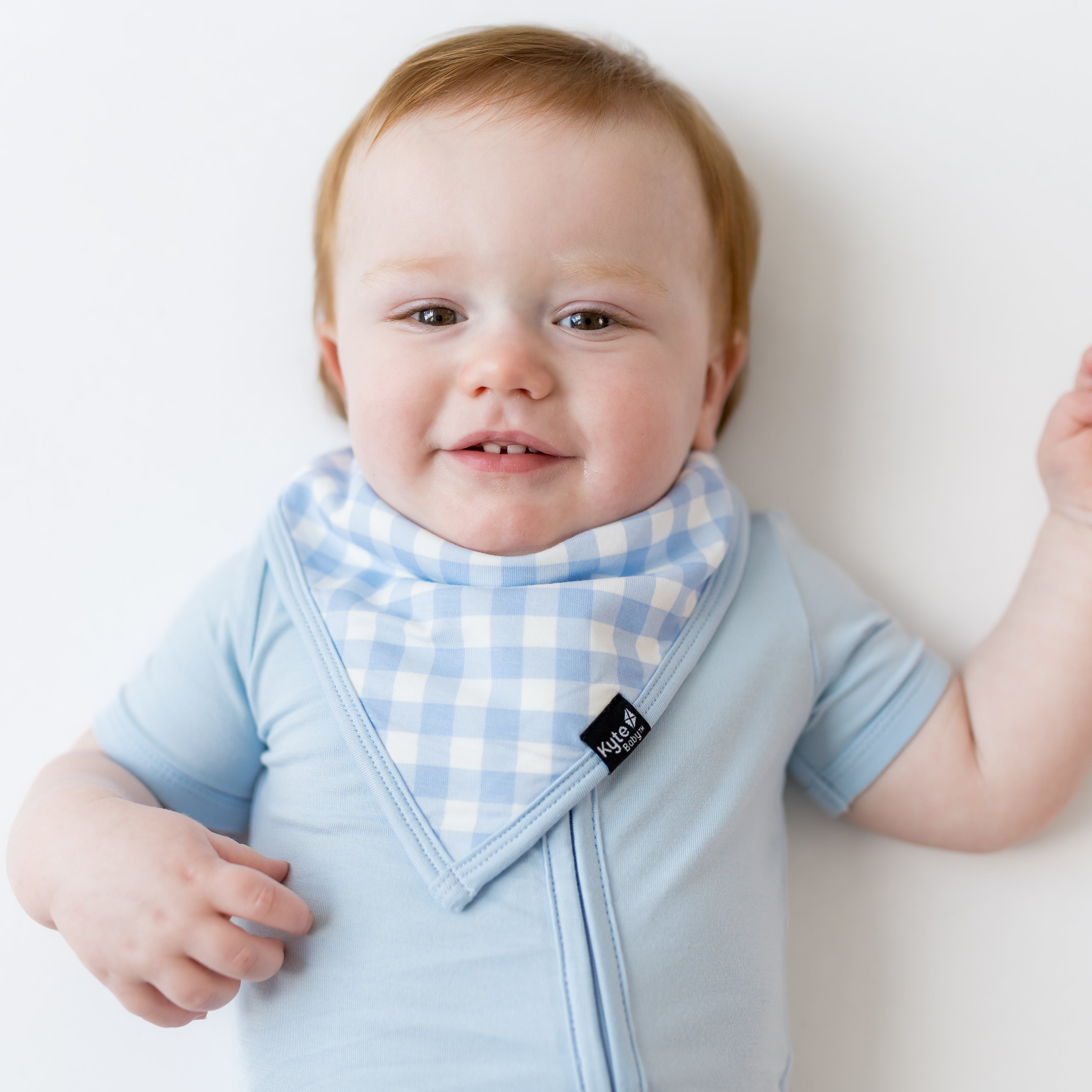 Infant wearing the Bib in Gingham Breeze overtop a Breeze romper